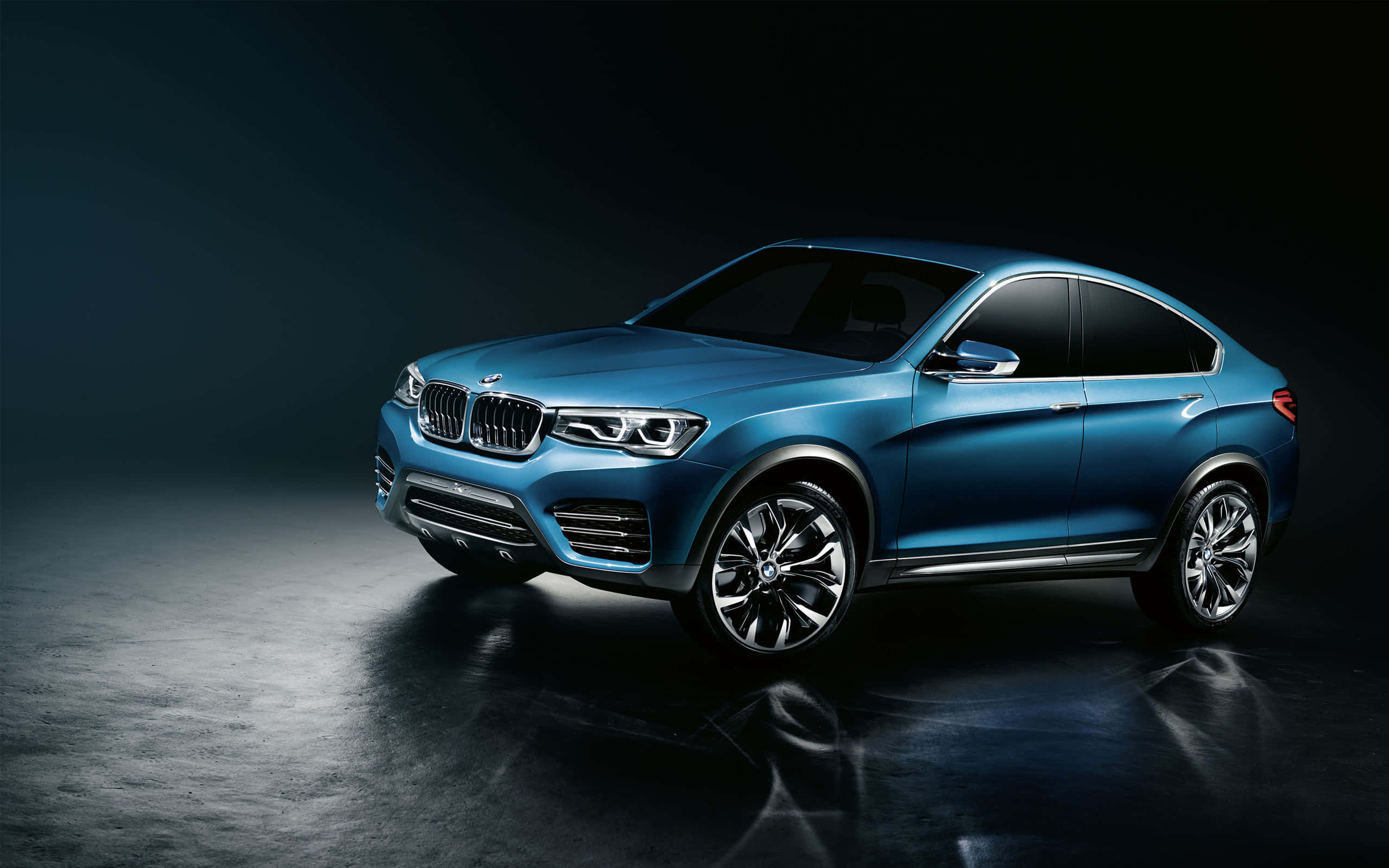Bmw X4 桌布 壁紙 — 一輛時尚的藍色BMW SUV轎跑車在戲劇性的工作室燈光下，在深色反光地板上閃耀。