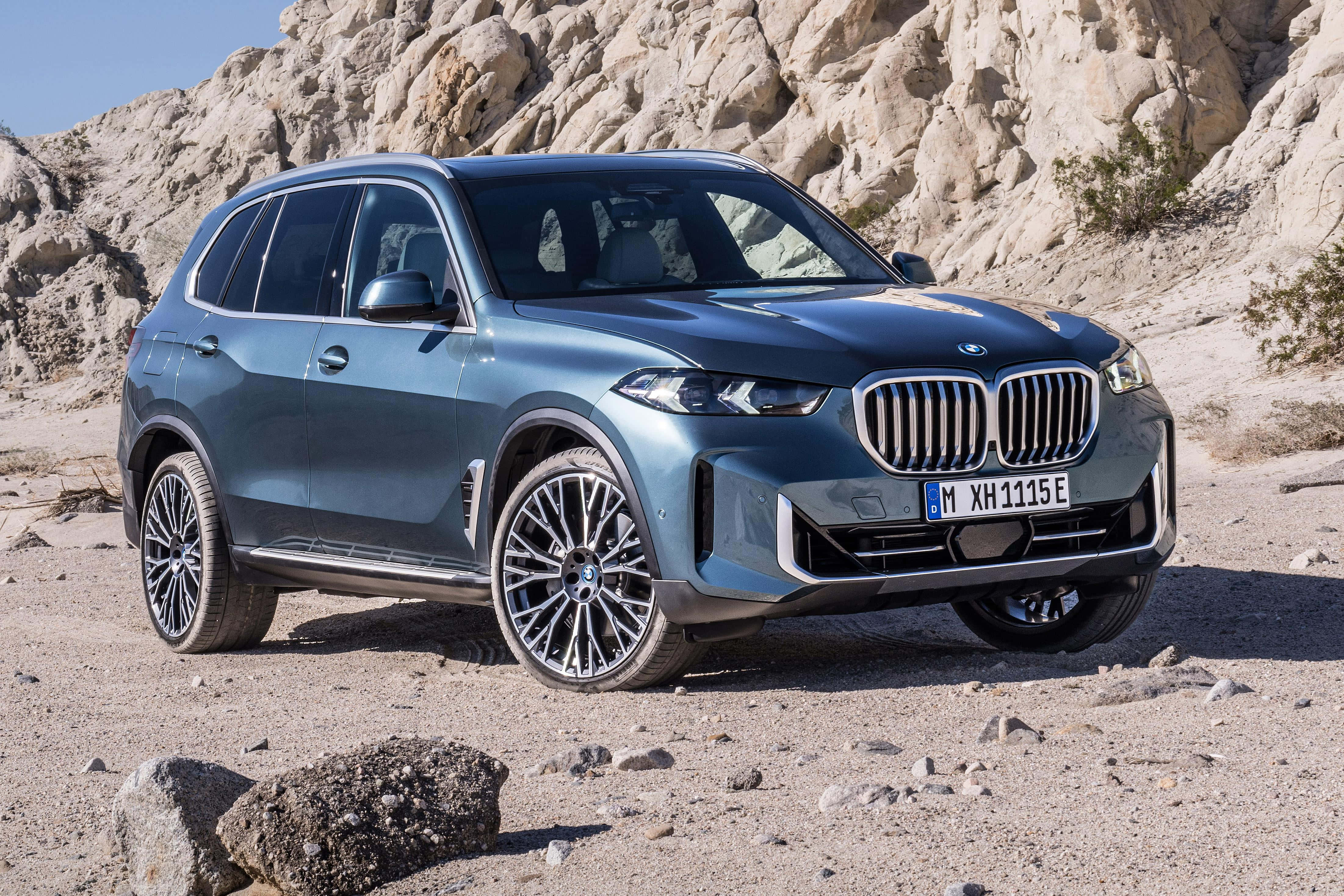 Bmw X5 桌布 壁紙 — 一輛時尚的藍色BMW X5 SUV停放在岩石沙漠地形上，在明亮的日光下。