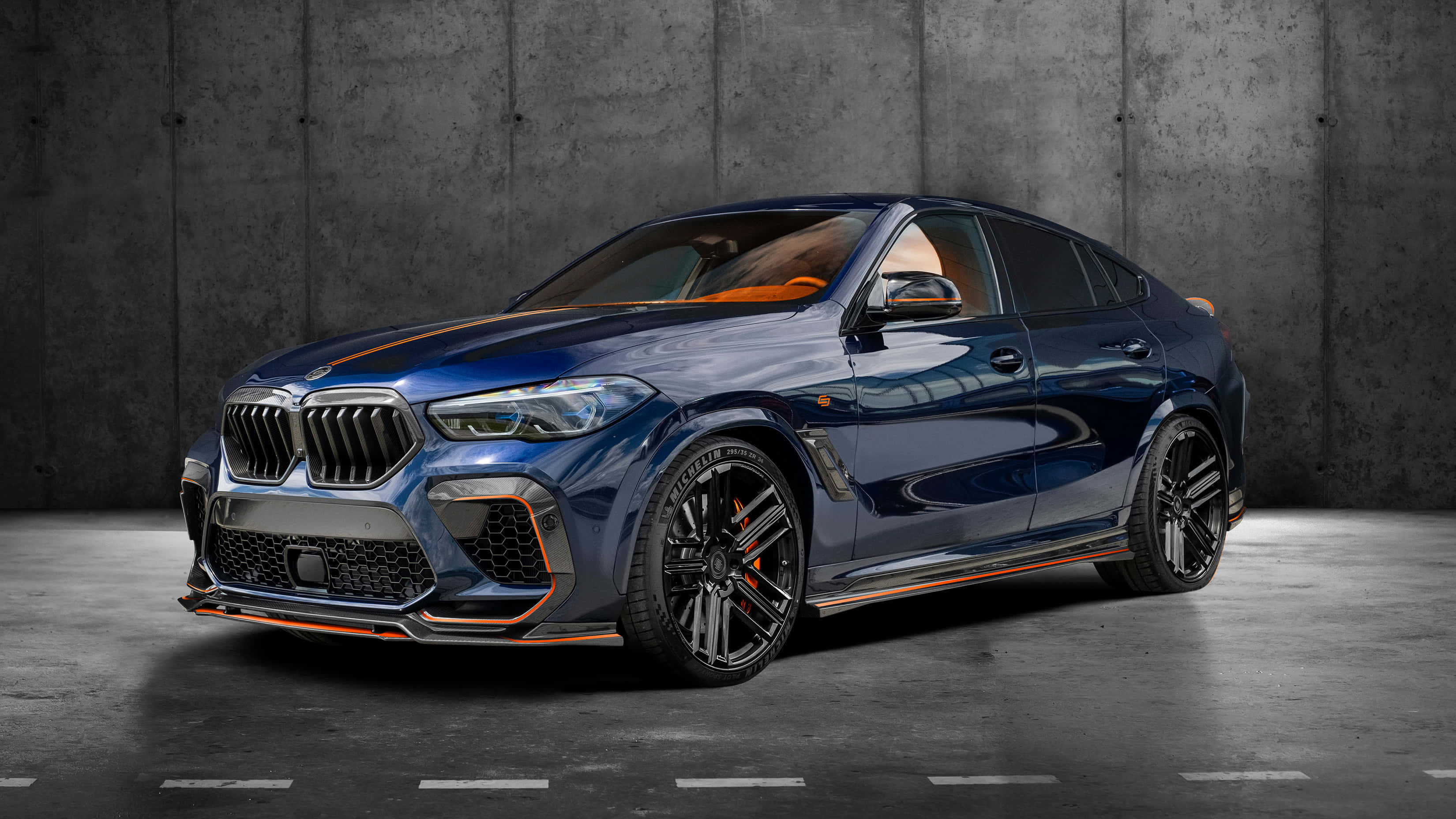 Bmw X6 M 桌布 壁紙 — 一輛時尚的藍色BMW X6 M帶有橙色點綴，在攝影棚燈光下對著紋理混凝土牆閃閃發光。
