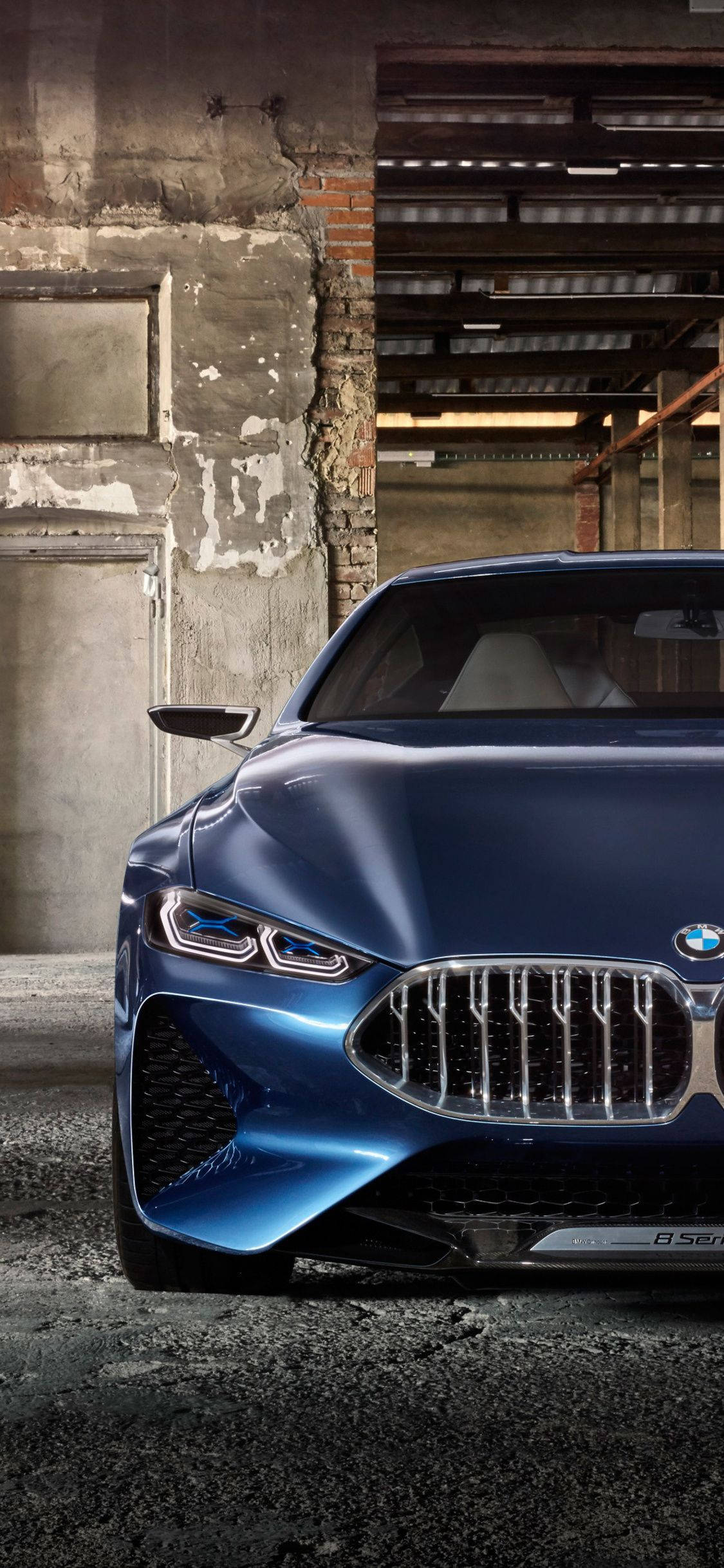BMW 動圖 桌布 壁紙 — 一輛時尚的藍色BMW概念車，配備發光車頭燈，矗立在一個粗糙的工業倉庫中，磚牆和混凝土裸露在外。
