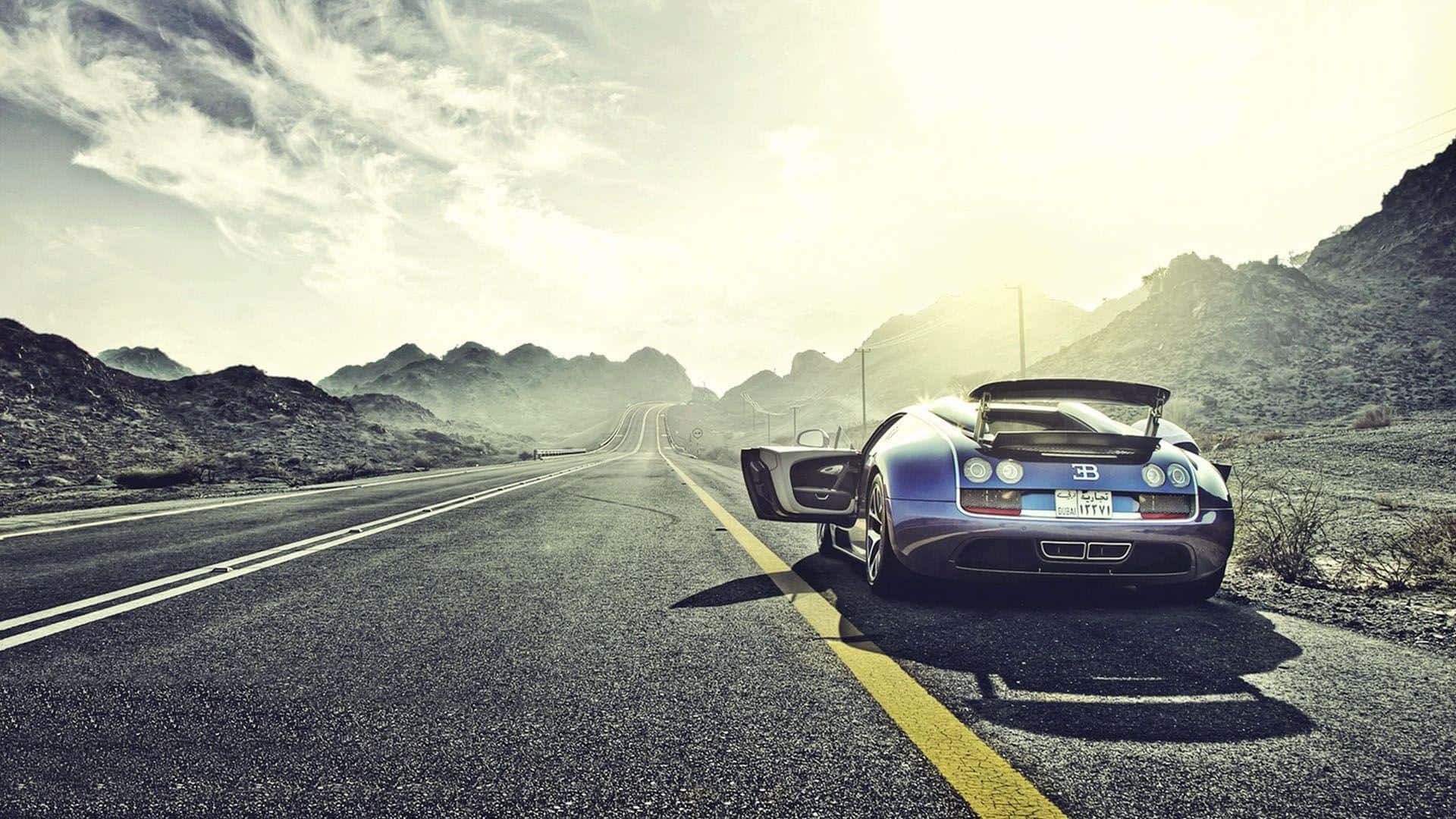 Bugatti Veyron 桌布 壁紙 — 一輛時尚的藍色Bugatti Veyron停泊在沙漠公路上，遠方有山脈，陽光明媚。
