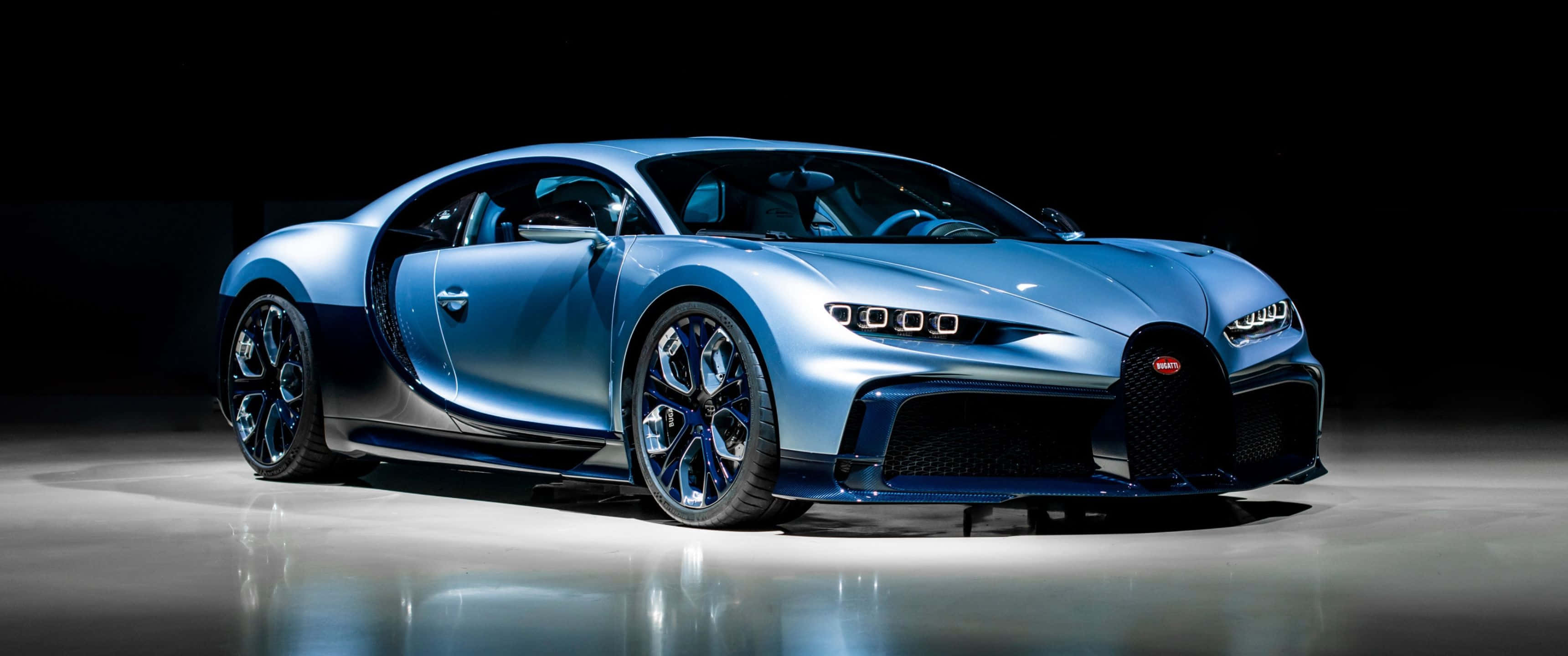 3440x1440p Bugatti 桌布 壁紙 — 一輛時尚的藍色Bugatti超跑在黑色背景下的反光地板上於攝影棚燈光下閃耀。