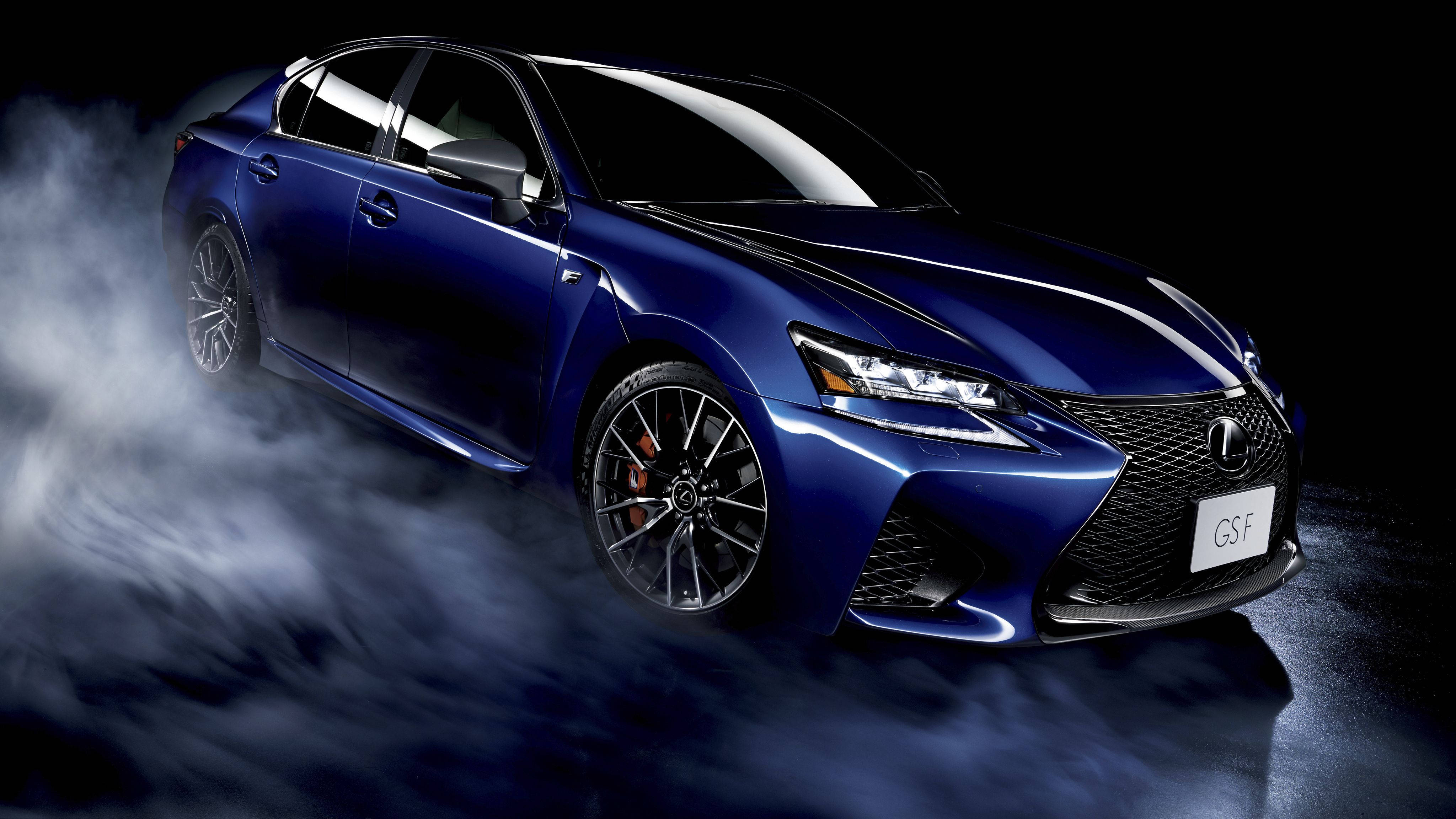 Lexus 桌布 壁紙 — 一輛時尚的藍色Lexus GS-F運動轎車從旋轉的煙霧中浮現，背景是黑暗的攝影棚。