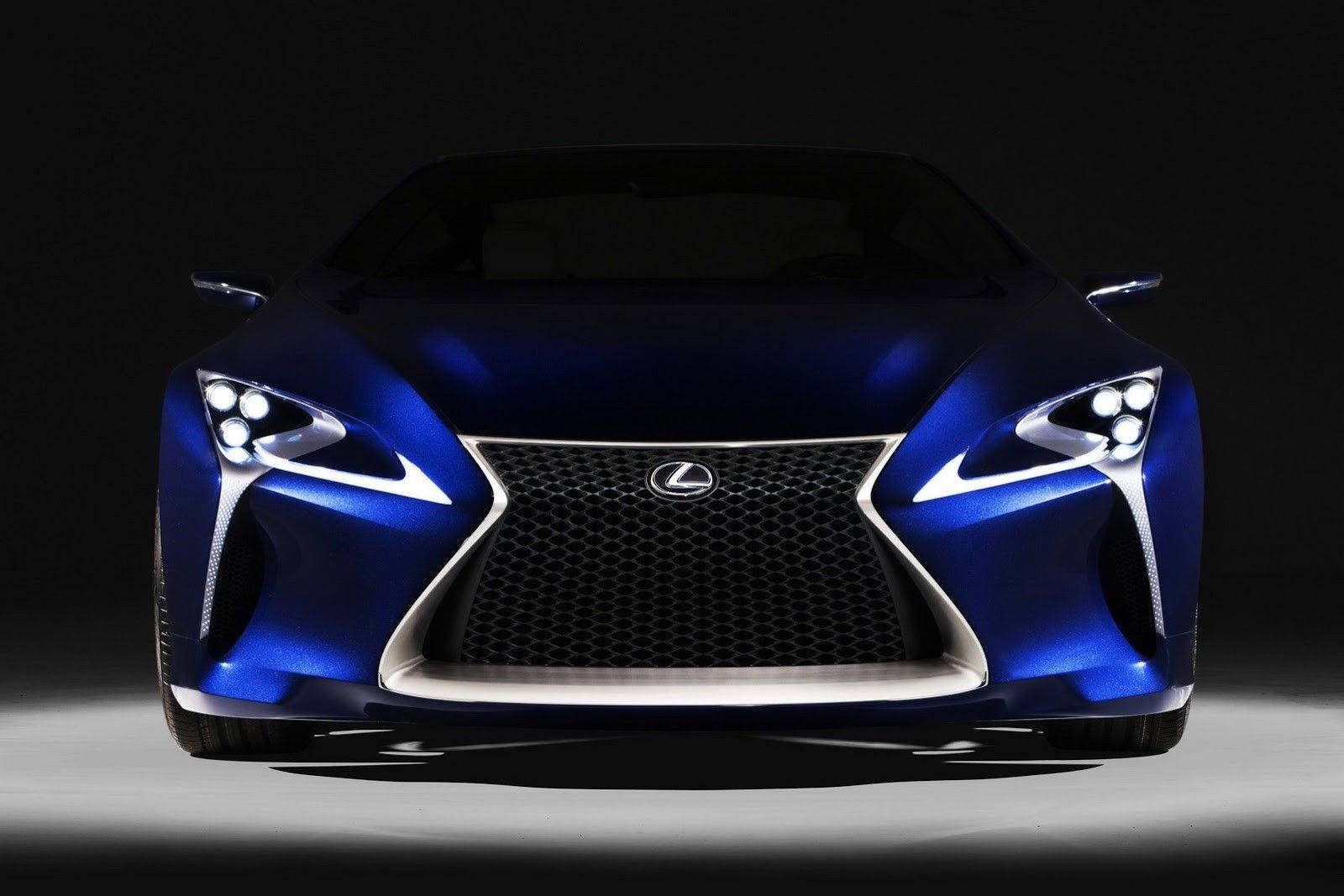 Lexus 桌布 壁紙 — 一輛時尚的藍色Lexus跑車，配備銳利頭燈和醒目水箱護罩，在黑色背景下戲劇性地照亮。