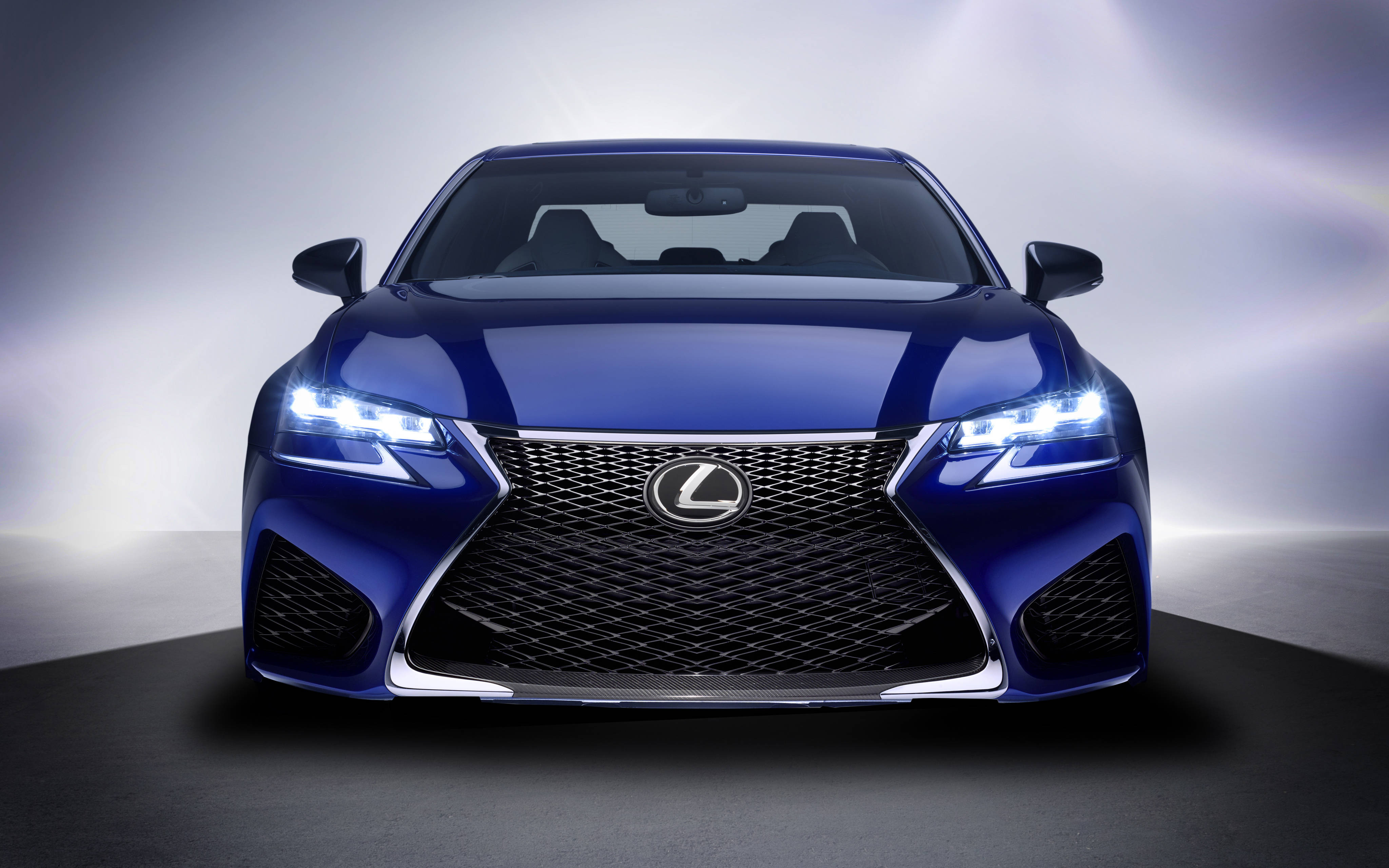i give up 桌布 壁紙 — 一輛時尚的藍色Lexus轎車正面朝前，帶有發光的車頭燈，背景是柔和的漸變工作室背景。