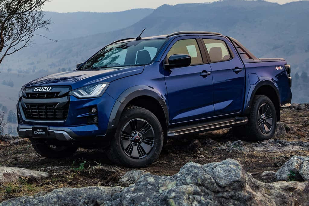 Isuzu 桌布 壁紙 — 一輛時尚的藍色五十鈴D-Max皮卡車停在岩石地形上，背景是霧氣繚繞的山脈。