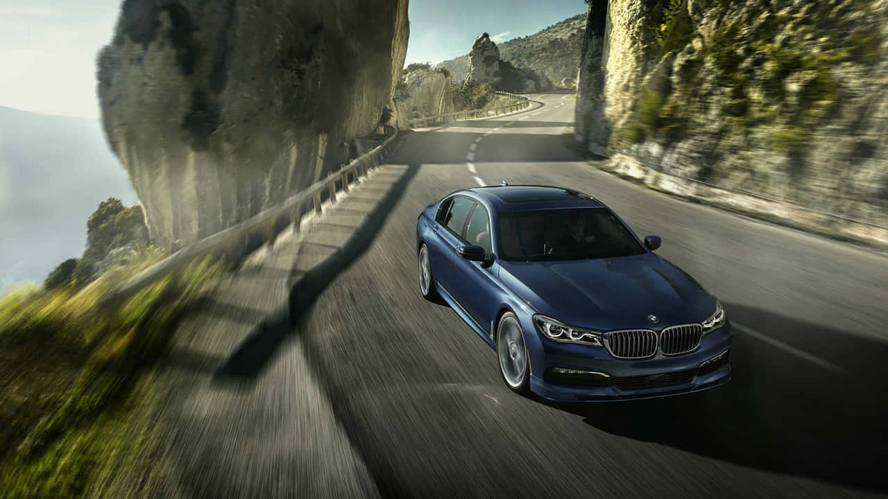 720p Bmw 桌布 壁紙 — 一輛時尚的藍色寶馬轎車沿著蜿蜒的山路疾馳，懸崖和綠意模糊掠過。