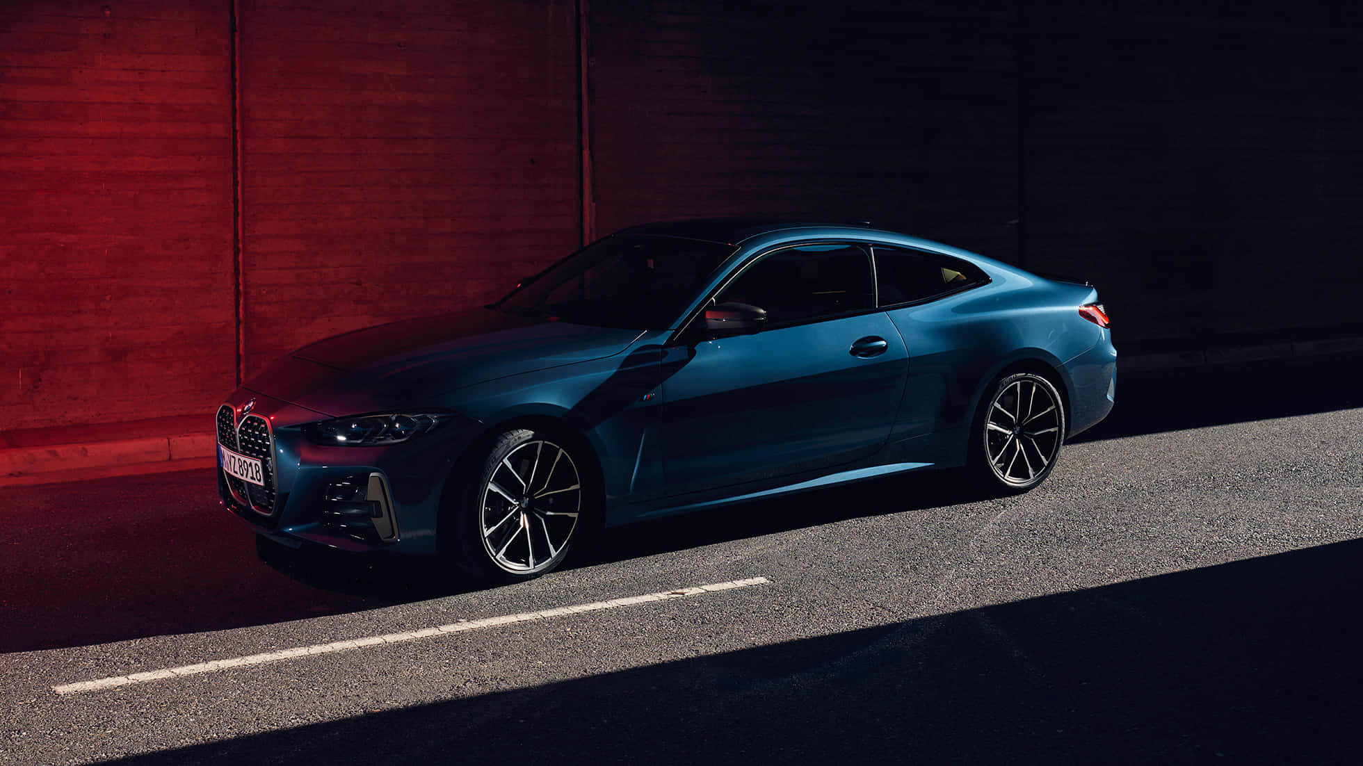 Bmw 440i 桌布 壁紙 — 一輛時尚的藍色寶馬雙門轎跑車停在瀝青路上，旁邊是紅磚牆，光線效果戲劇性。