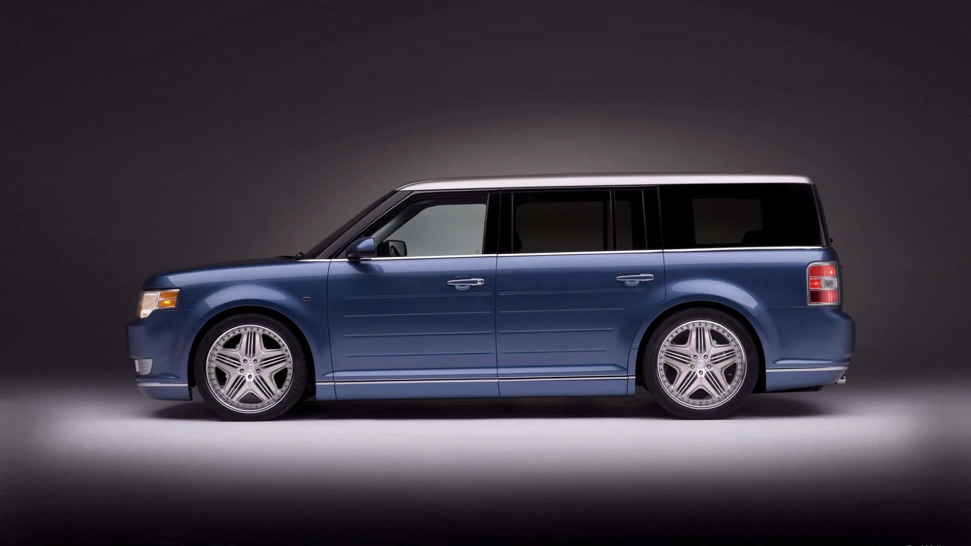 Ford Flex 桌布 壁紙 — 一輛時尚的藍色旅行車配備銀色輪圈，在戲劇性燈光的攝影棚中展示。
