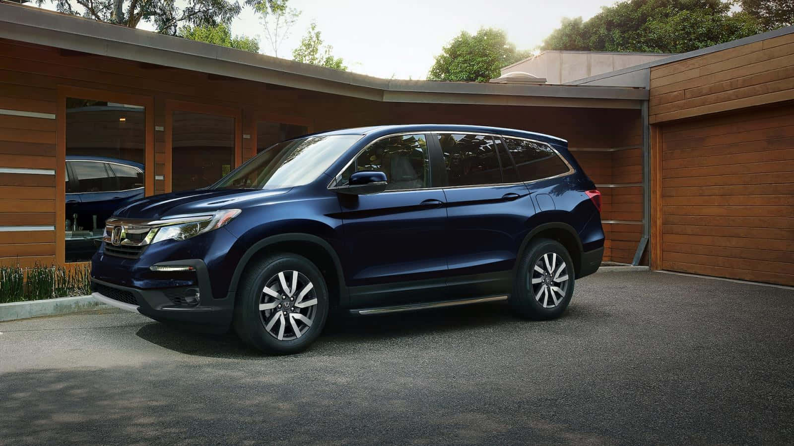 Honda Pilot 桌布 壁紙 — 一輛時尚的藍色本田Pilot SUV停在一棟帶玻璃門和碎石車道的現代木屋前。