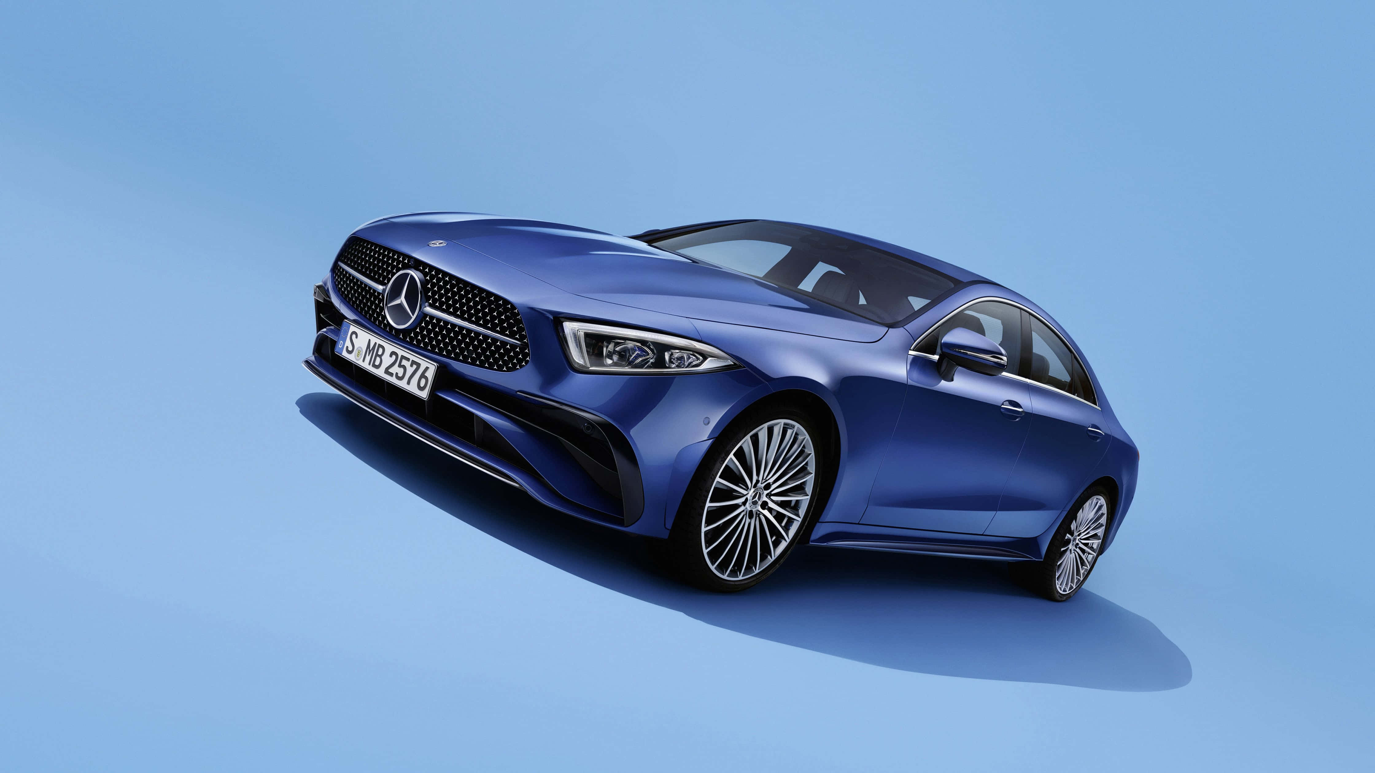 Mercedes 桌布 壁紙 — 一輛時尚的藍色梅賽德斯-奔馳轎車在純淺藍色背景下的攝影棚燈光中閃閃發光。