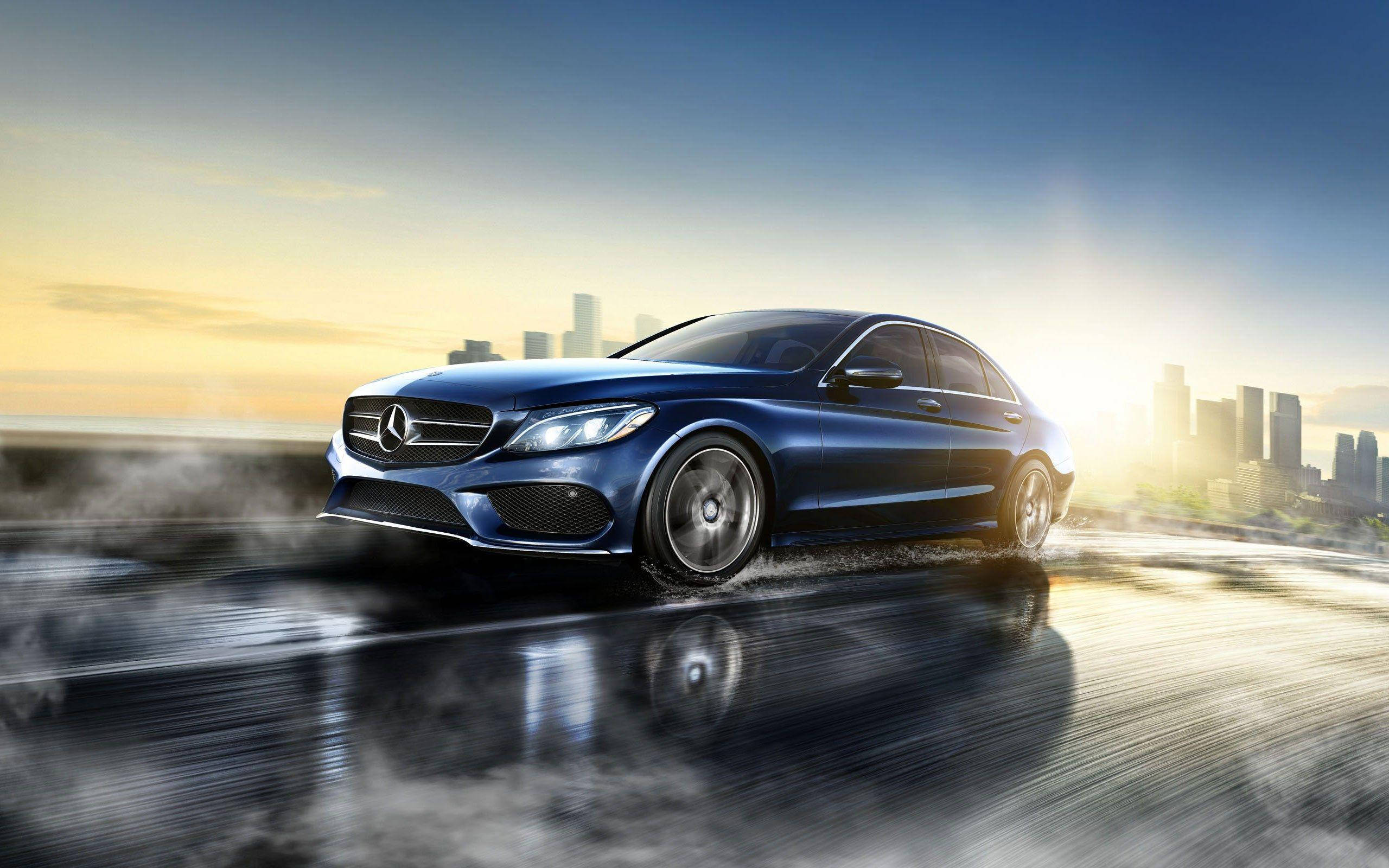 Mercedes Benz C300 桌布 壁紙 — 一輛時尚的藍色梅賽德斯轎車在日落時分駛過濕漉漉的城市道路，背景中摩天大樓閃閃發光。