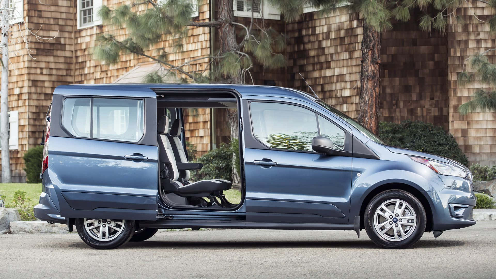 Ford Transit 桌布 壁紙 — 一輛時尚的藍色福特 Transit Connect 廂型車停在街上，側門打開，露出內部座椅和後方的木屋。
