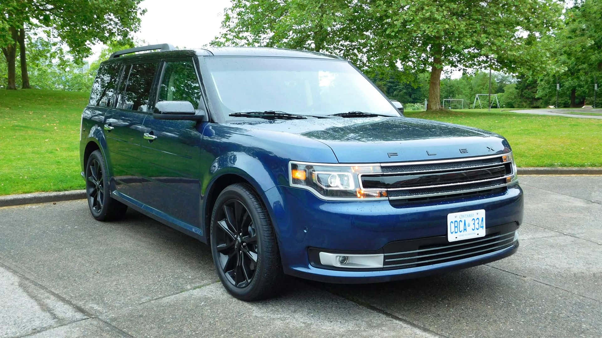 Ford Flex 桌布 壁紙 — 一輛時尚的藍色福特Flex SUV停放在鋪砌的車道上，背景有茂密的綠樹和草地。
