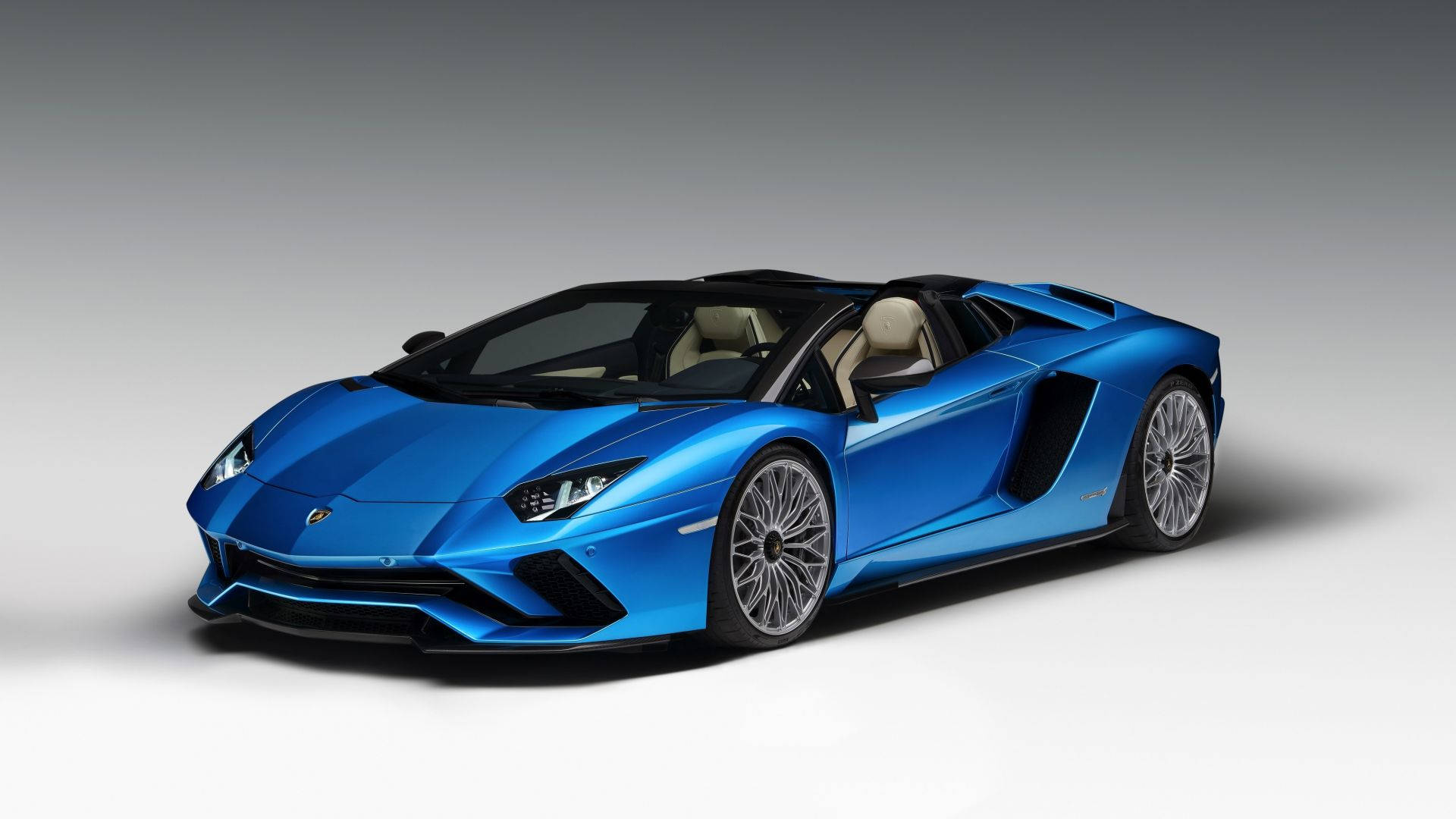 藍色 桌布 壁紙 — 一輛時尚的藍色藍寶堅尼 Aventador Roadster 在攝影棚燈光下閃耀，車頂敞開，銀色輪圈捕捉光輝。