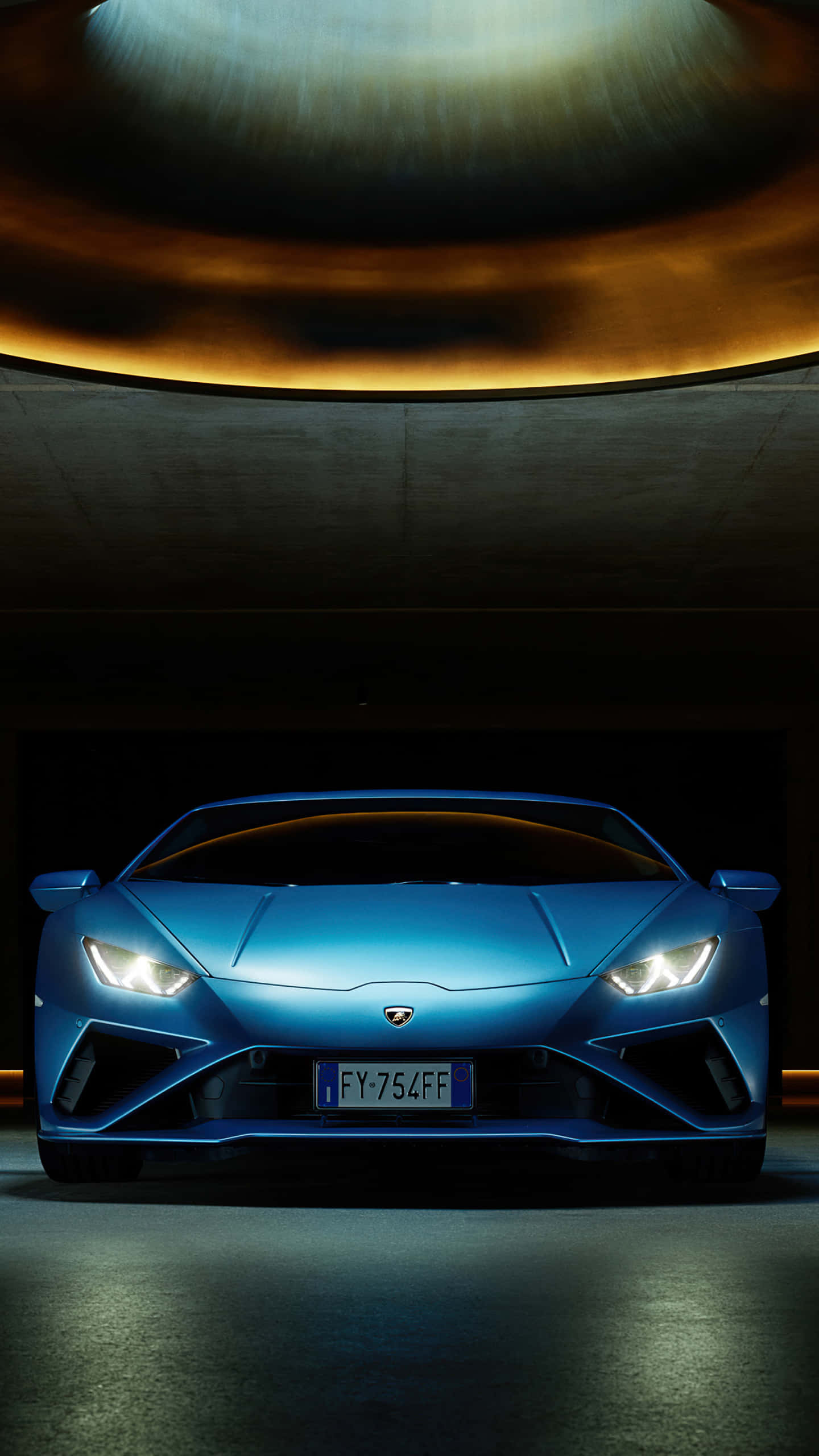 Blue Lamborghini iPhone 桌布 壁紙 — 一輛時尚的藍色藍寶堅尼跑車在黑暗的現代車庫中，在溫暖的圓形燈光下閃閃發光。