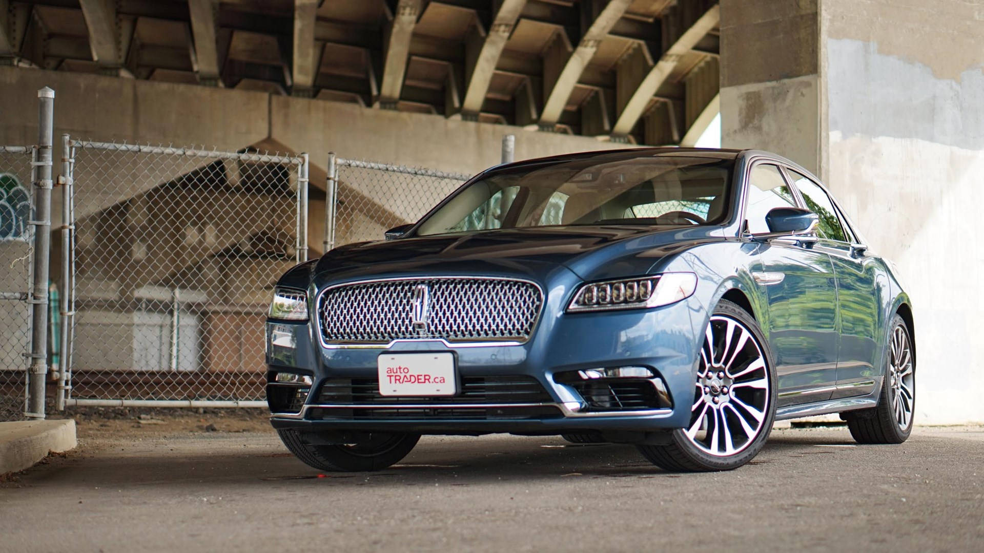 cars 桌布 壁紙 — 一輛時尚的藍色豪華轎車停在混凝土天橋下，背景是鐵絲網圍欄。