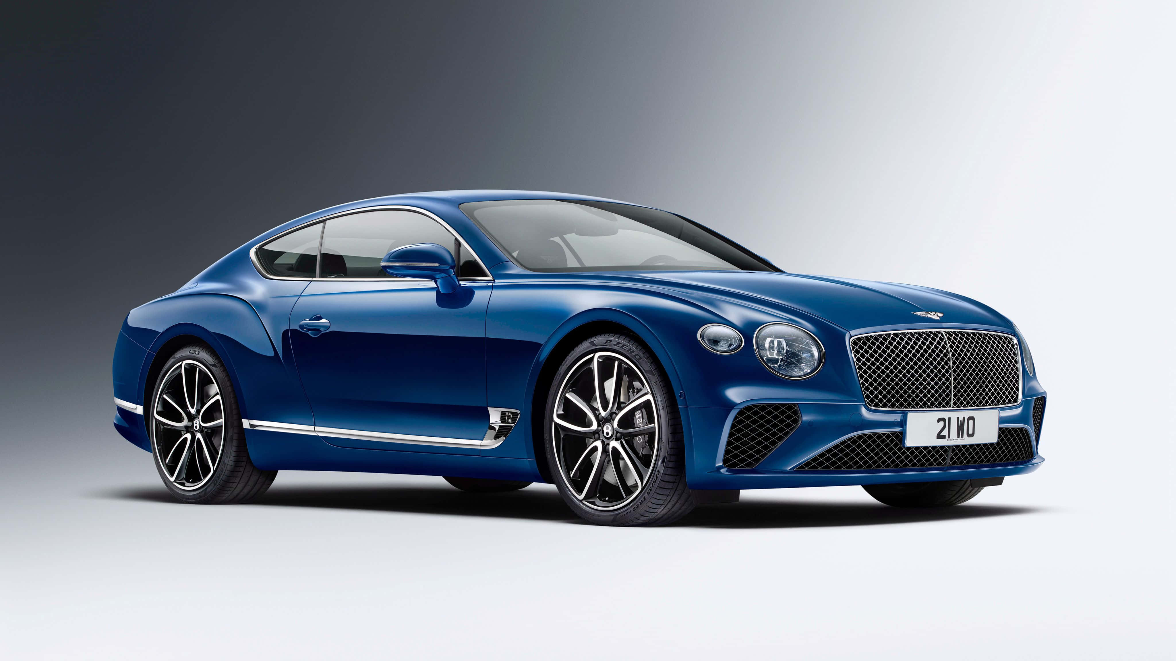 賓利 桌布 壁紙 — 一輛時尚的藍色賓利 Continental GT 雙門轎跑車在攝影棚燈光下，在漸變灰色和白色背景上閃閃發光。