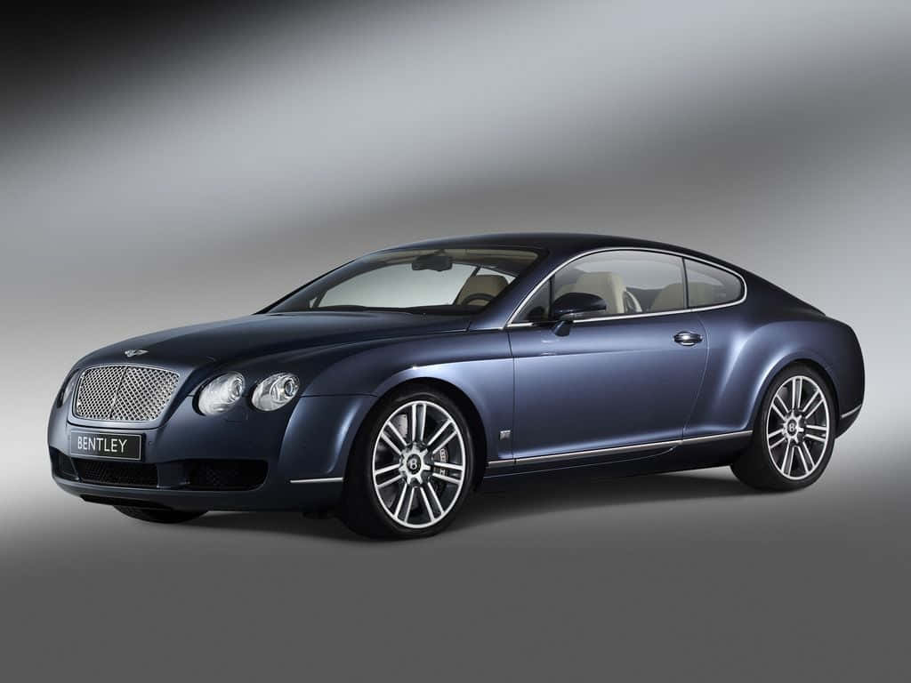 Diamond Car 桌布 壁紙 — 一輛時尚的藍色賓利 Continental GT 雙門轎跑車在漸變灰色背景前的攝影棚燈光下閃閃發光。