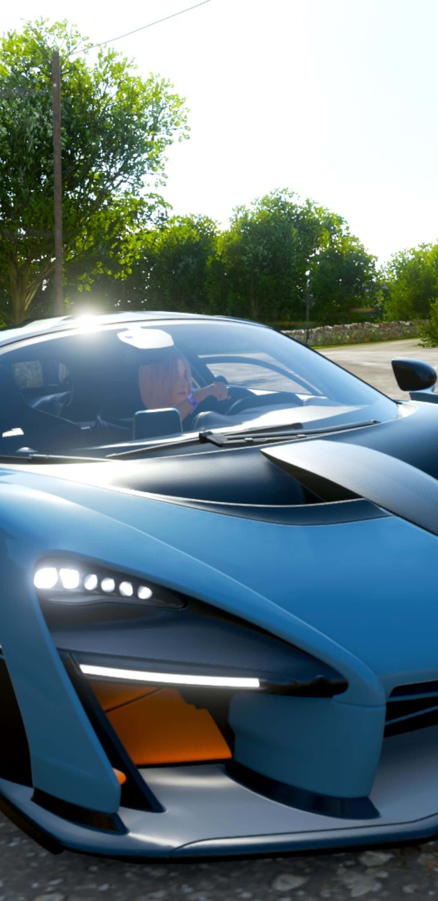 Pixel 3xl Forza Horizon 4 桌布 壁紙 — 一輛時尚的藍色跑車，帶有發光的車頭燈，在明亮的陽光下停放在戶外，背景是綠樹。