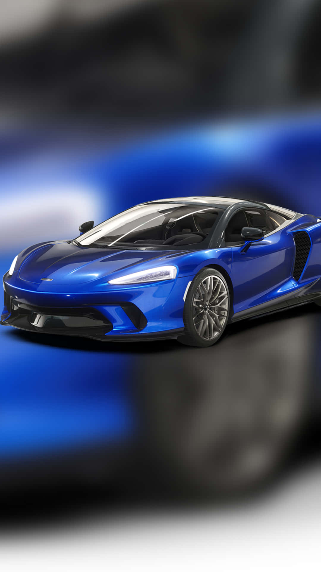 Blue Car 桌布 壁紙 — 一輛時尚的藍色跑車，配備發光的車頭燈和空氣動力學曲線，在模糊的動態背景中滑行。