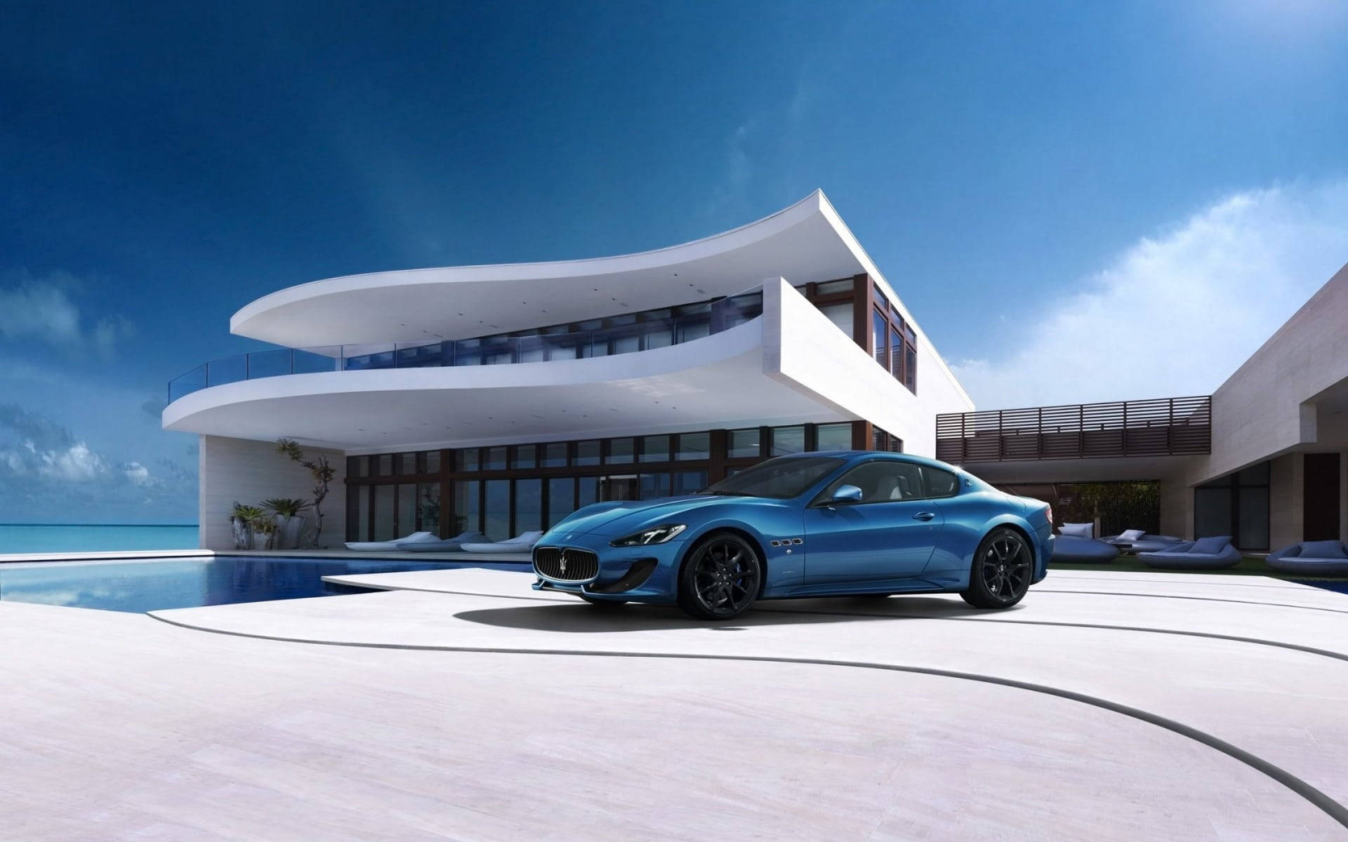 Luxury House 桌布 壁紙 — 一輛時尚的藍色跑車停泊在彎曲的車道上，旁邊是一座現代白色別墅，設有游泳池和海洋景觀，在晴朗的藍天下。