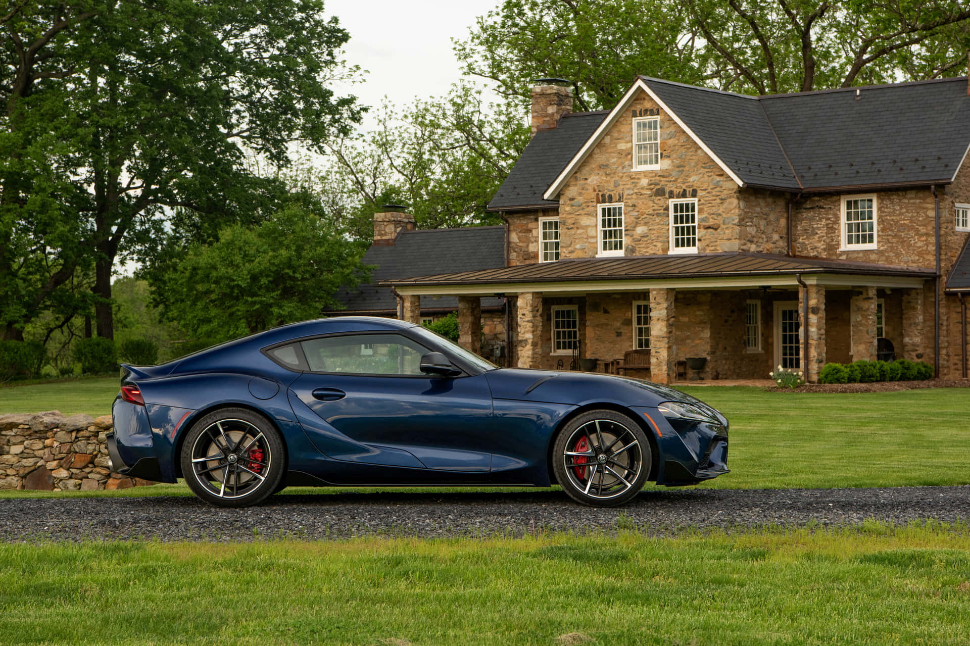 藍色跑車停泊在石屋前面的綠色草坪上。 — Toyota Supra Mk4 壁紙