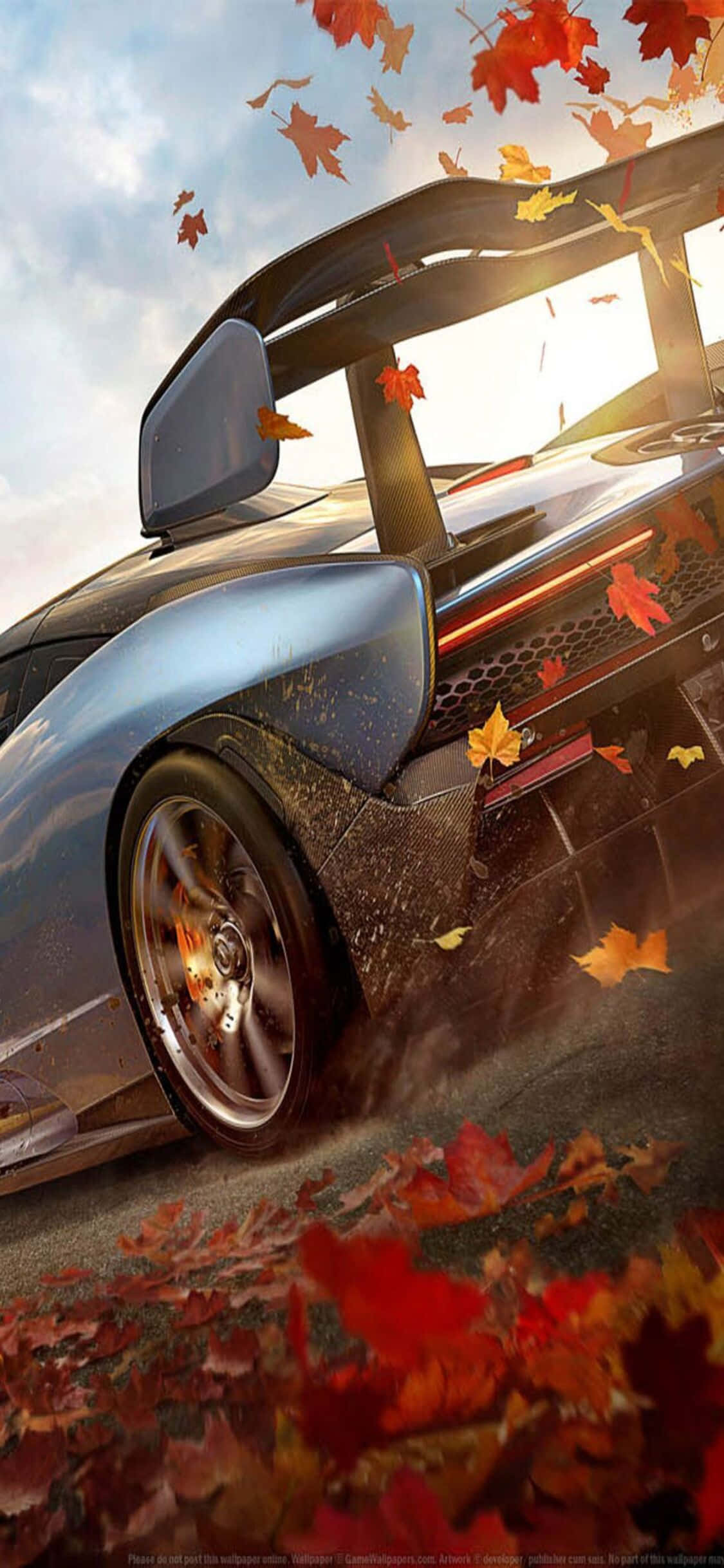 Forza Gaming 桌布 壁紙 — 一輛時尚的藍色跑車在森林中疾馳，秋葉在車輪周圍旋轉。