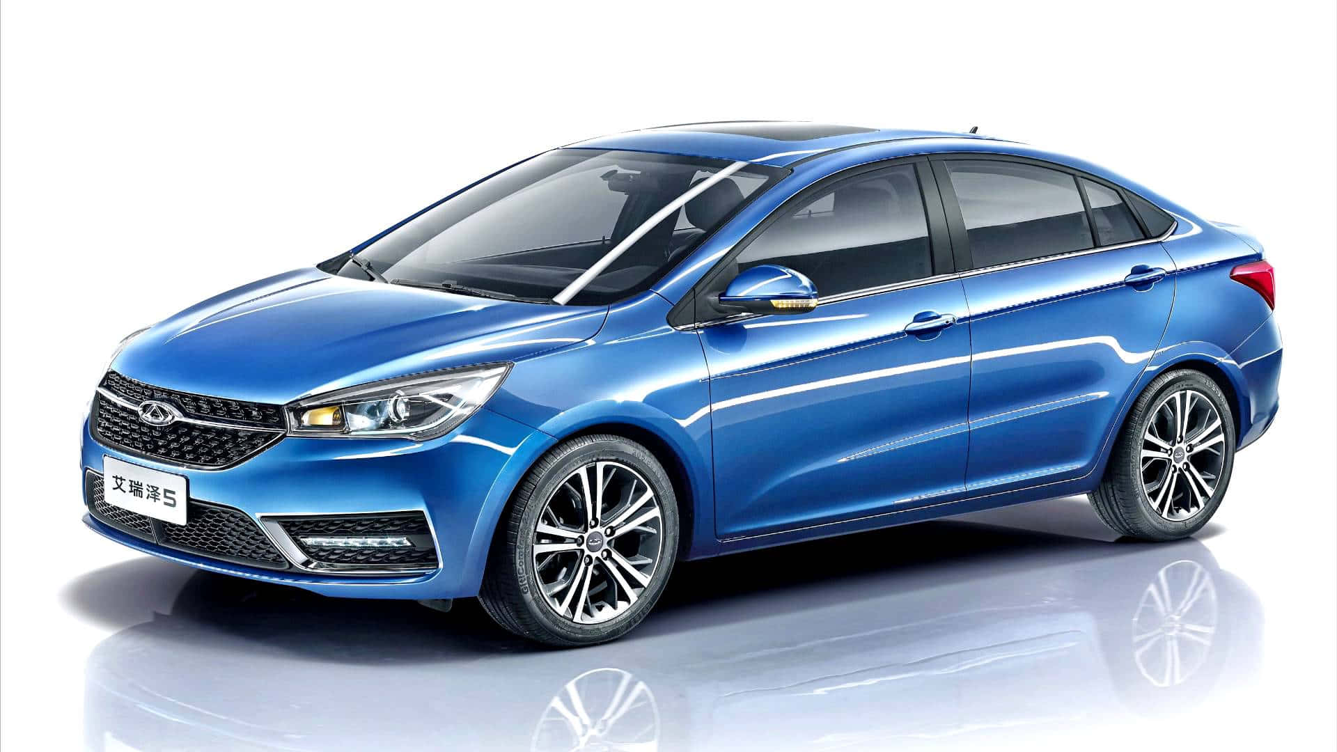 Chery 桌布 壁紙 — 一輛時尚的藍色轎車，帶有鍍鉻裝飾和合金輪圈，展示在反光的白色工作室地板上。