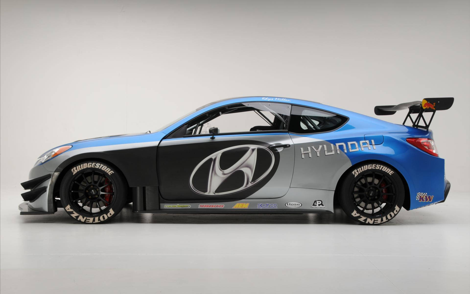 Hyundai 桌布 壁紙 — 一輛時尚的藍黑現代賽車，帶有贊助商貼紙和大型後翼，在中性工作室背景下準備好加速。