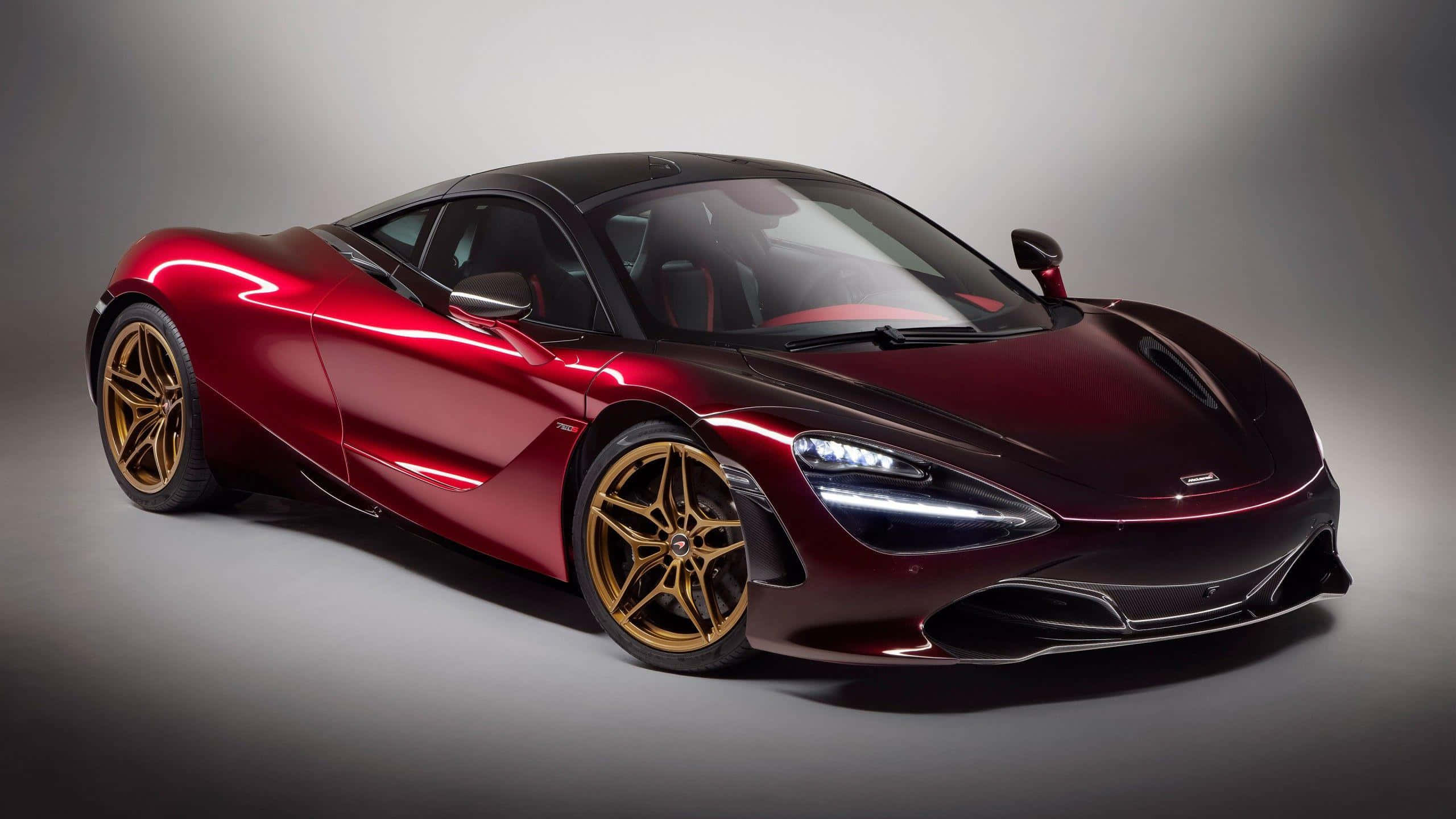 Mclaren 720s 桌布 壁紙 — 一輛時尚的酒紅色McLaren 720S跑車配金色輪圈，在攝影棚燈光下於中性灰色背景前閃閃發光。