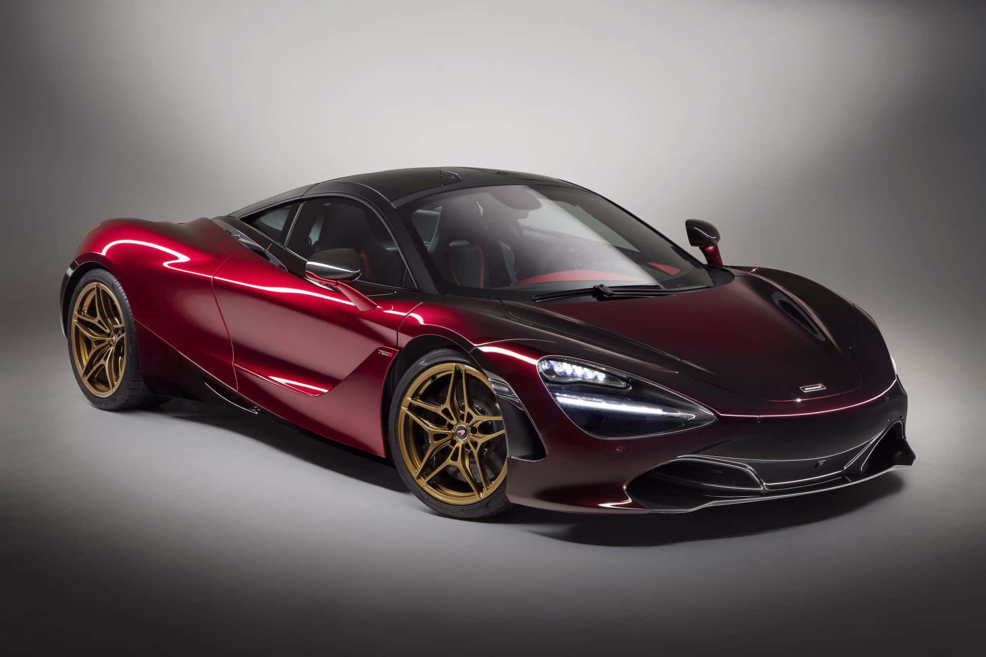 紅色動圖 桌布 壁紙 — 一輛時尚的酒紅色McLaren 720S跑車搭配金色輪圈，在灰色背景的攝影棚燈光下閃耀。