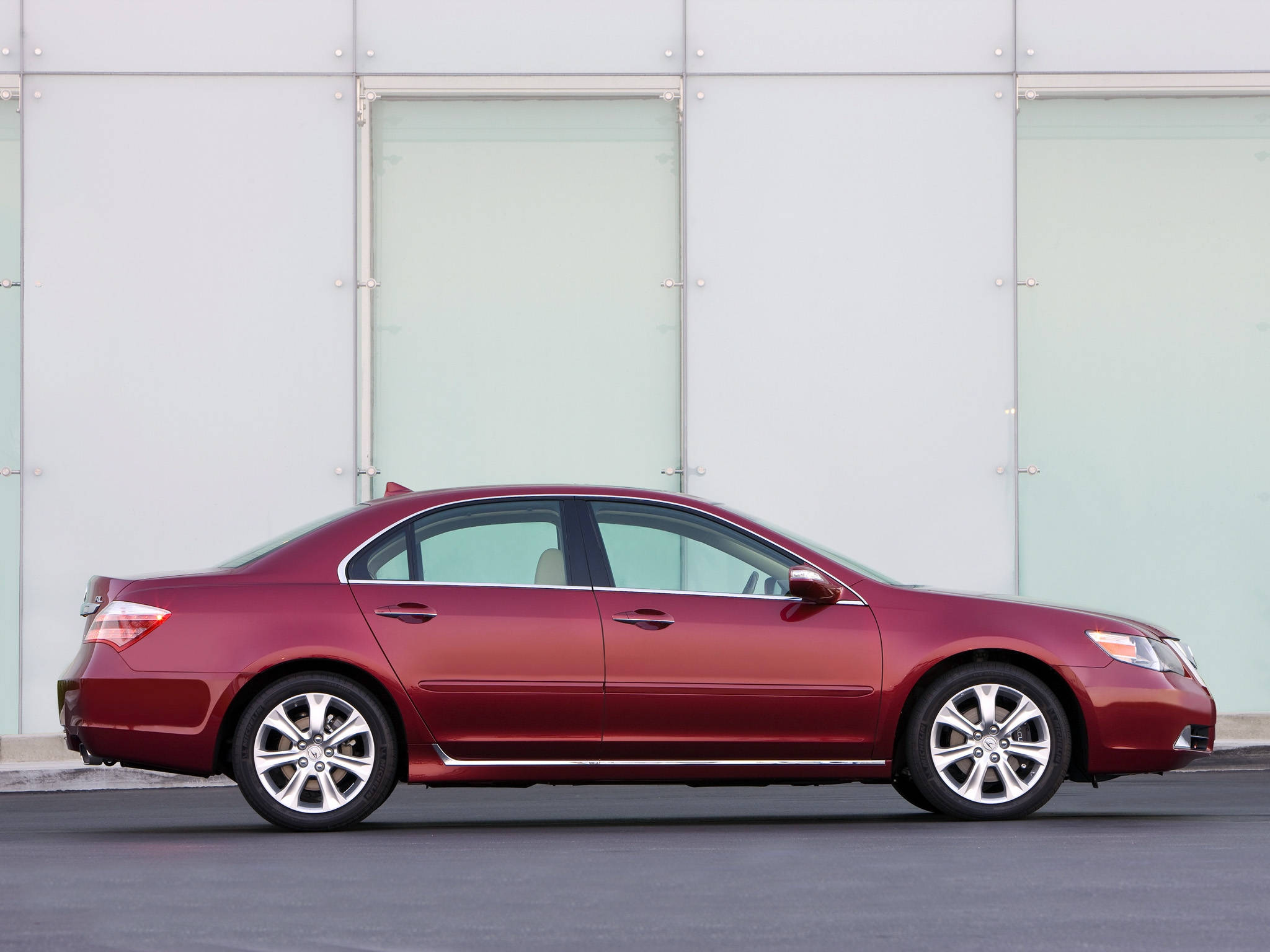 Acura 桌布 壁紙 — 一輛時尚的酒紅色轎車停放在現代玻璃和金屬建築前，在明亮的日光下。