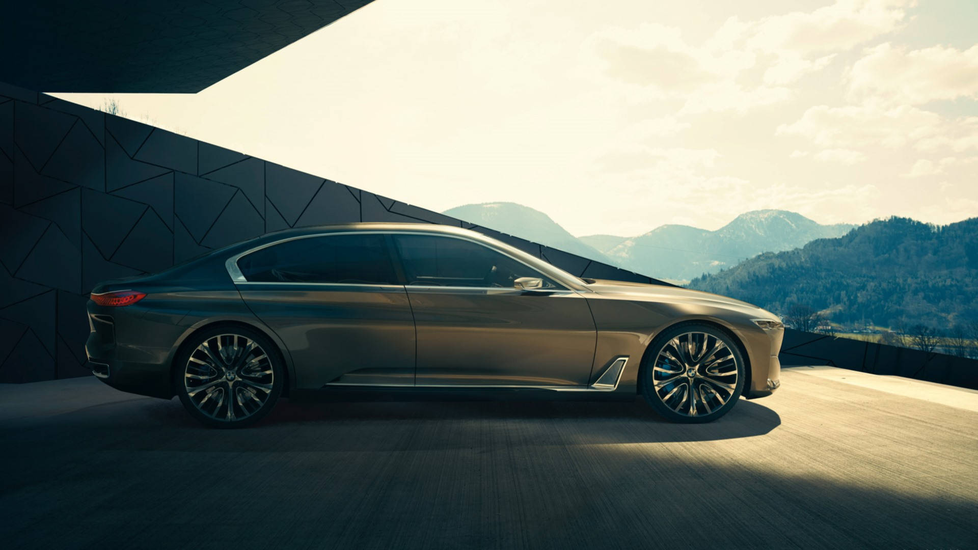 Luxury 桌布 壁紙 — 一輛時尚的金屬色轎車停放在現代幾何平台上，背景是山脈，天空柔和金黃。