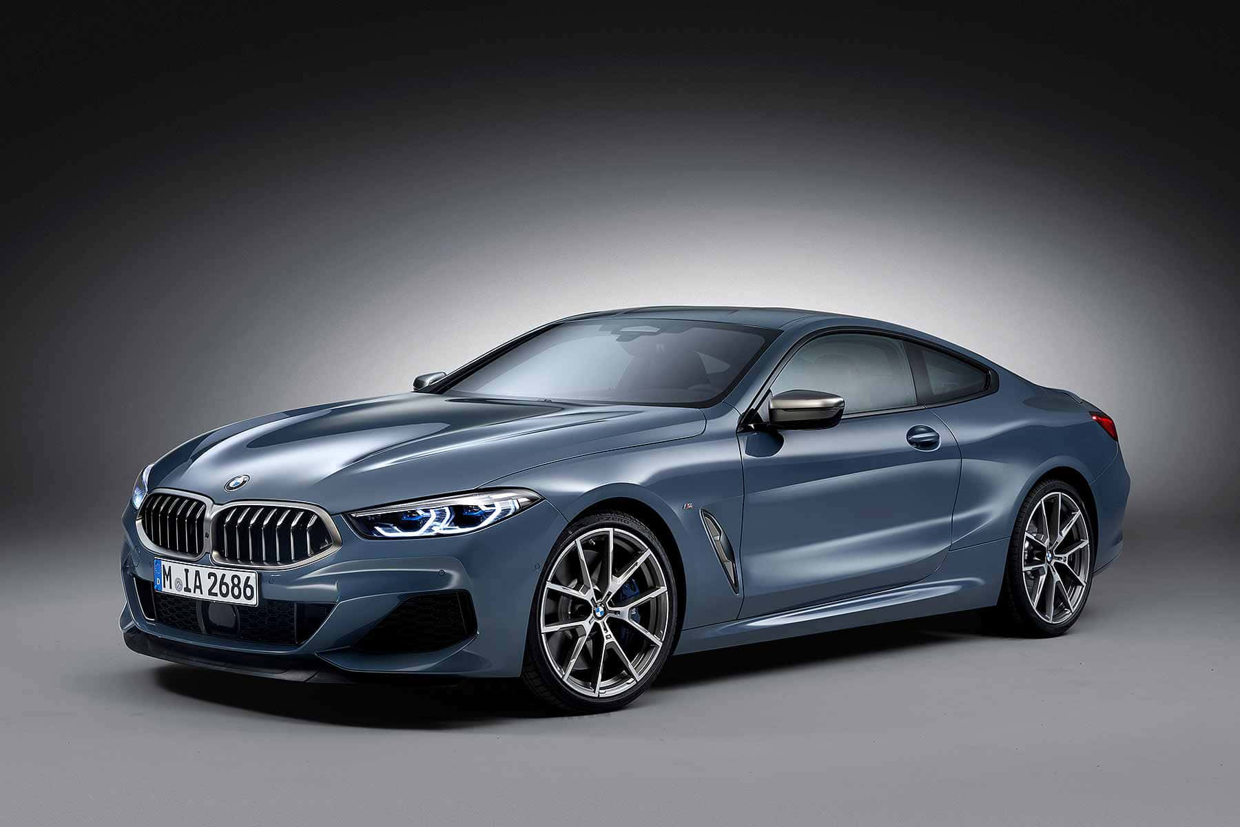 Bmw 8 Series 桌布 壁紙 — 一輛時尚的金屬藍色BMW 8系列轎跑車在攝影棚燈光下，於深色漸層背景前閃閃發光。
