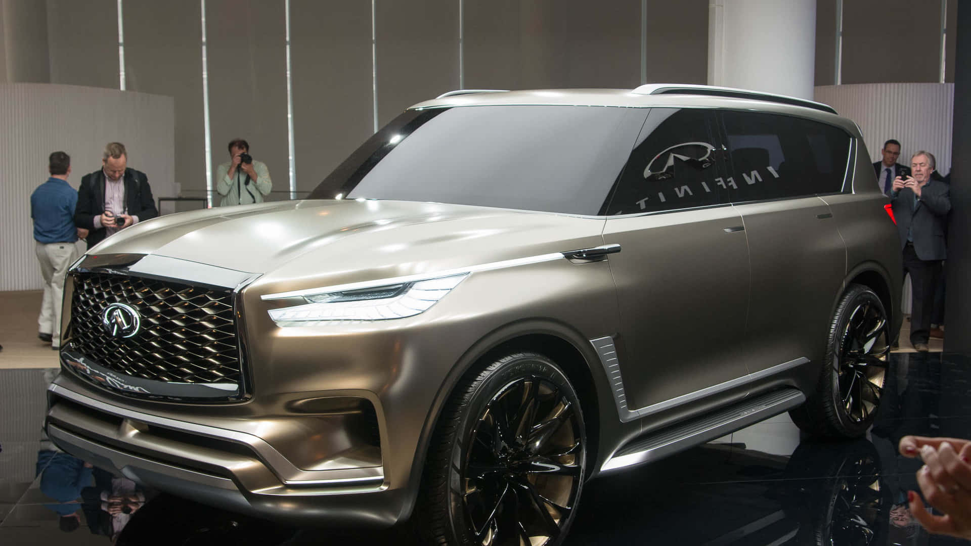 Infiniti Qx80 桌布 壁紙 — 一輛時尚的金屬金色 Infiniti SUV 在車展上展出，攝影師們正在捕捉其未來感設計。