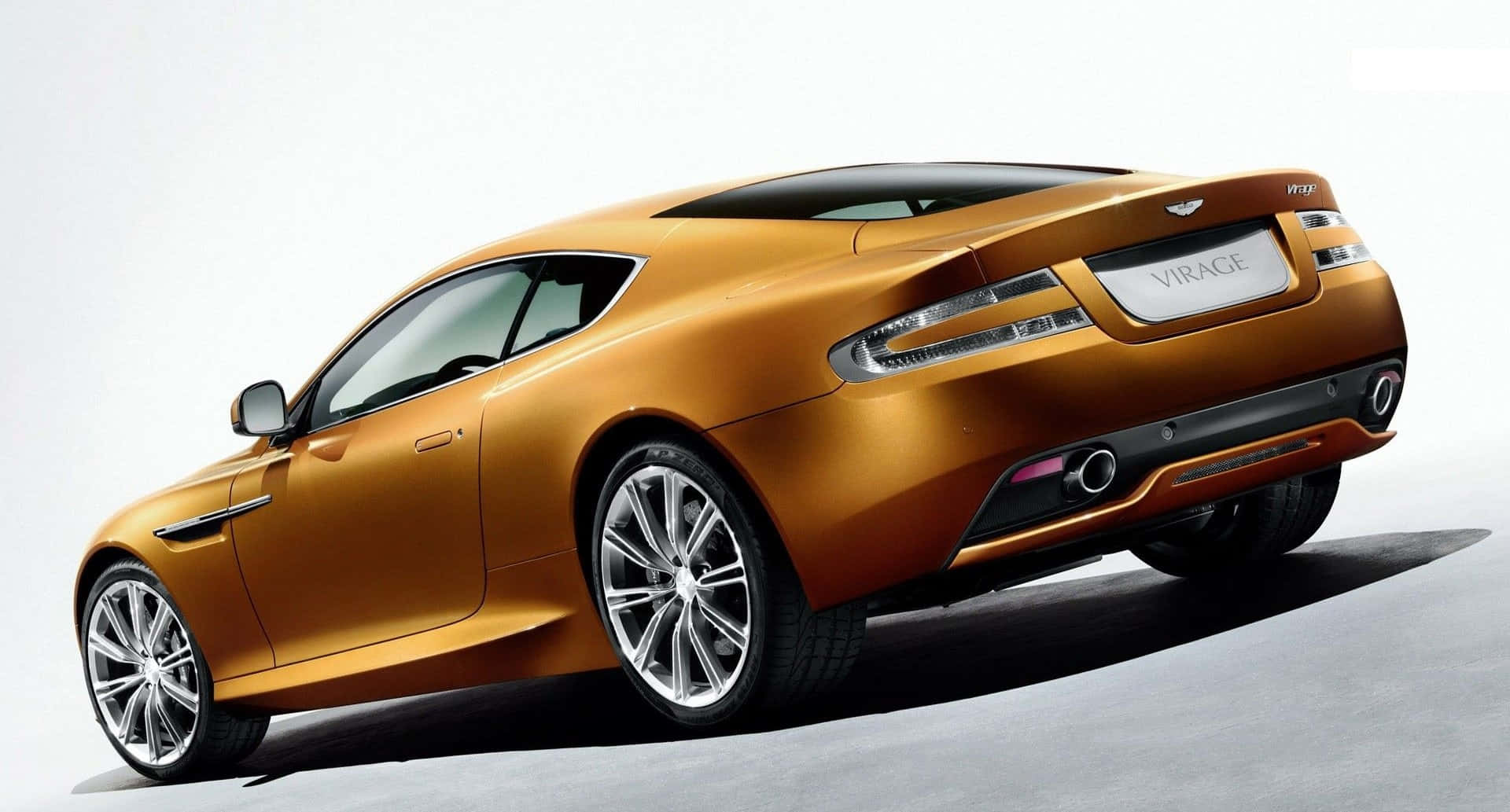 Back 桌布 壁紙 — 一輛時尚的金色 Aston Martin Virage 雙門轎跑車在工作室燈光下以潔白背景展示。
