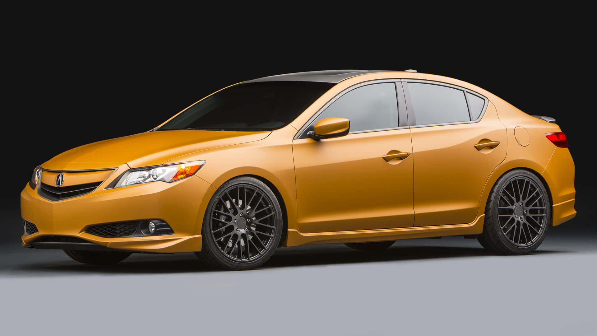 Acura Ilx 桌布 壁紙 — 一輛時尚的金色轎車配備黑色輪圈和有色車窗，在深色背景下展現奢華與性能。