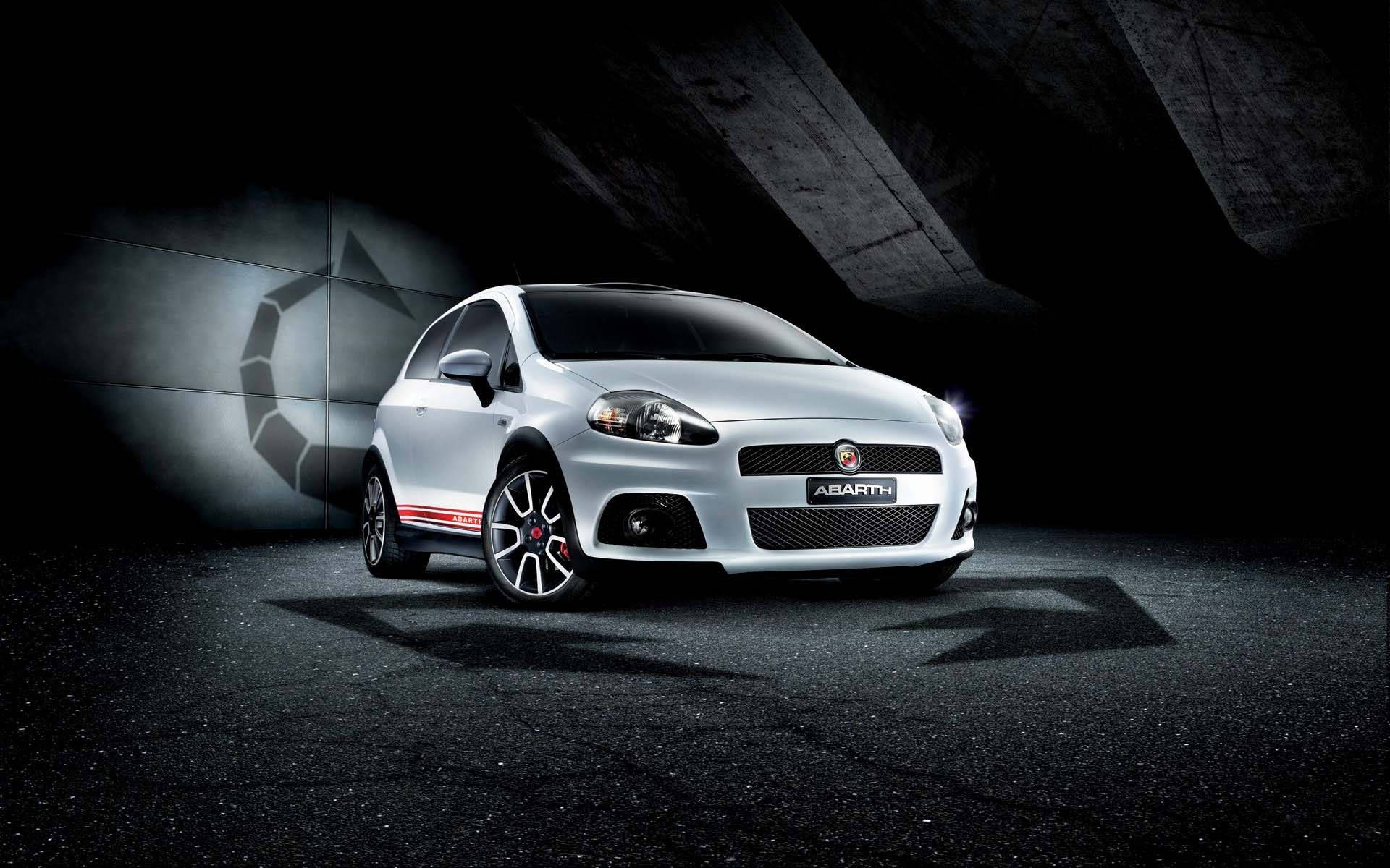 Fiat 桌布 壁紙 — 一輛時尚的銀色 Abarth 跑車在黑暗的混凝土隧道中，在戲劇性的聚光燈下閃閃發光，帶有幾何陰影投影。