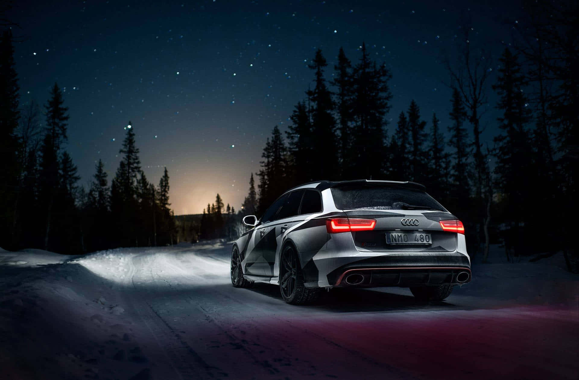 奧迪 桌布 壁紙 — 一輛時尚的銀色 Audi RS6 Avant 在星空下穿越雪地森林，紅色尾燈閃爍。