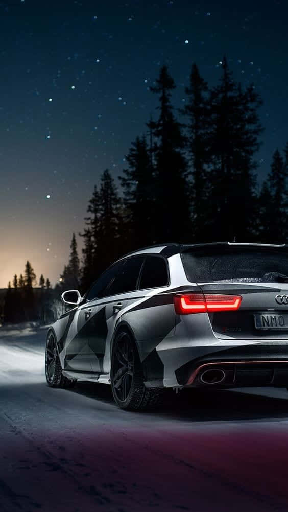 奧迪 桌布 壁紙 — 一輛時尚的銀色 Audi 旅行車在星空下行駛於白雪覆蓋的樹林中，紅色尾燈閃爍發光。