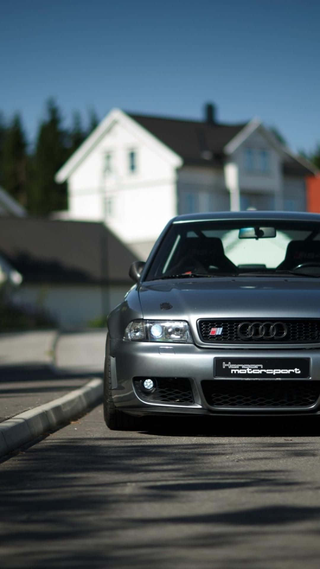 Audi S4 桌布 壁紙 — 一輛時尚的銀色 Audi 跑車停放在陽光明媚的住宅街道上，背景是一棟白色房屋。