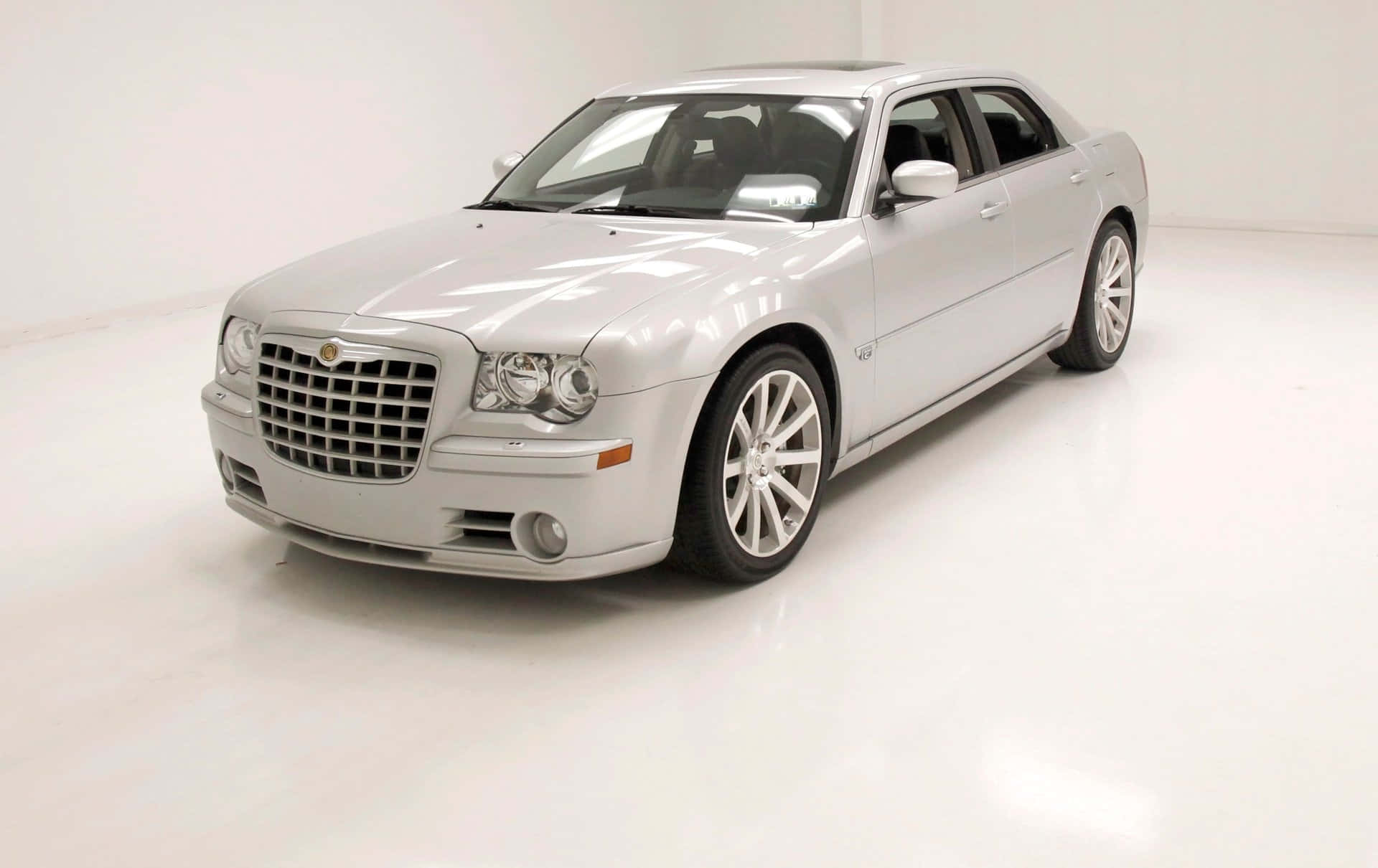 Chrysler 桌布 壁紙 — 一輛時尚的銀色 Chrysler 300 轎車在明亮的攝影棚燈光下，在潔白無瑕的地板上閃閃發光。