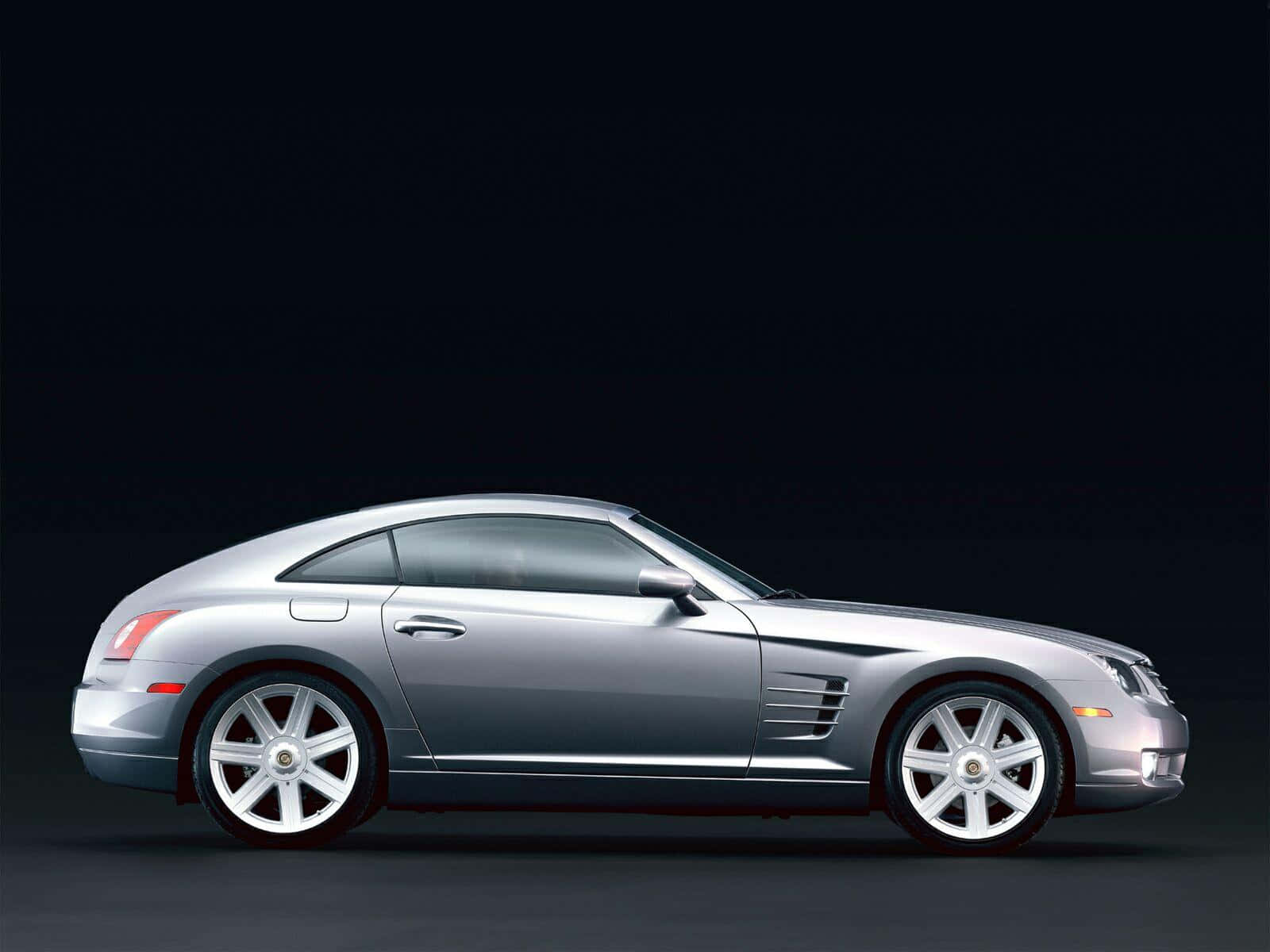 Chrysler Crossfire 桌布 壁紙 — 一輛時尚的銀色 Chrysler Crossfire 跑車，在深色攝影棚背景下以側面輪廓展示。