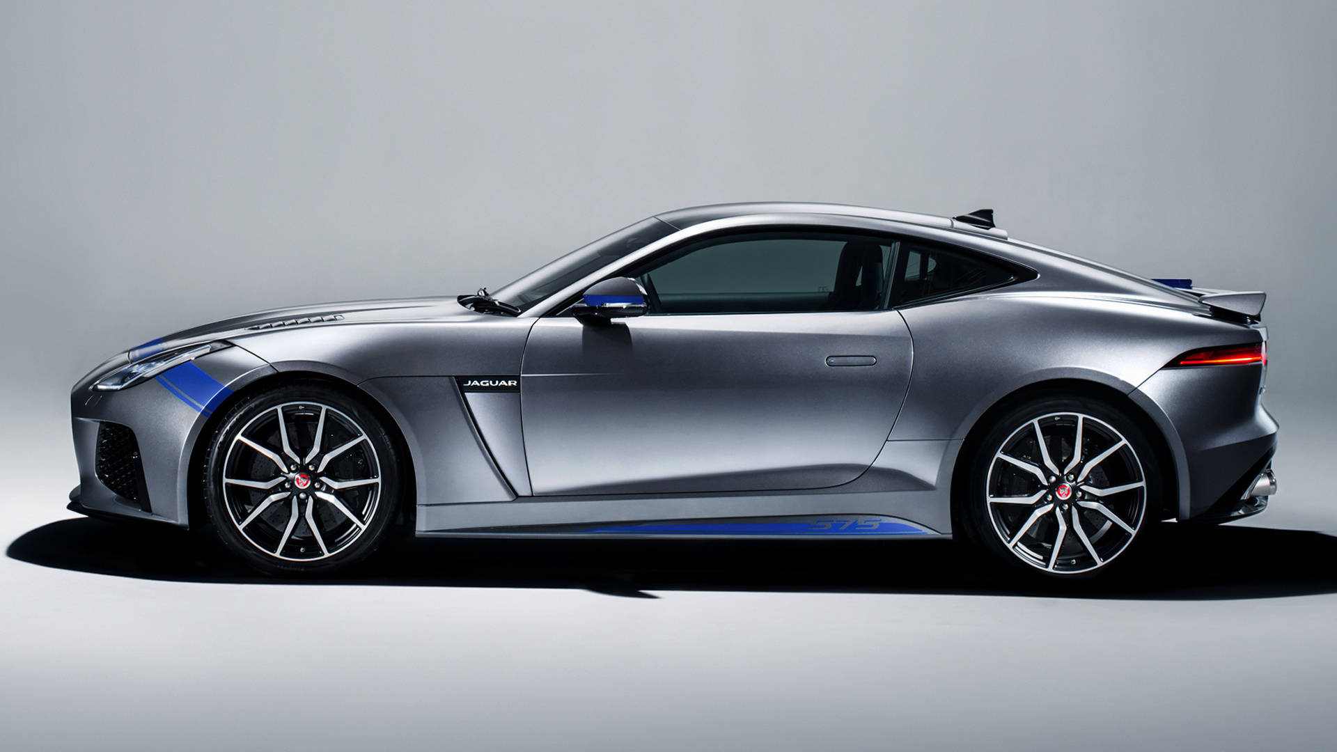 圖形 桌布 壁紙 — 一輛時尚的銀色 Jaguar F-Type 跑車帶有藍色點綴，在極簡灰色工作室背景中以側面輪廓展示。