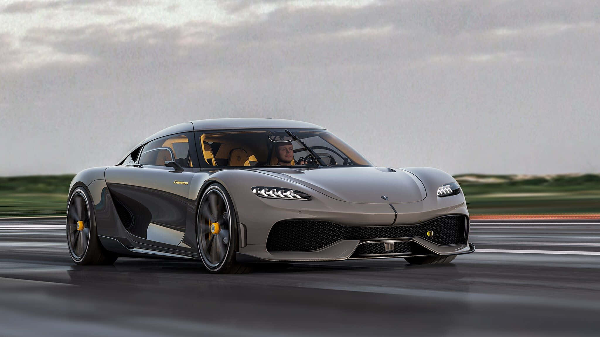 Koenigsegg 桌布 壁紙 — 一輛時尚的銀色 Koenigsegg Jesko 超跑在多雲的天空下沿著潮濕的賽道飛馳。