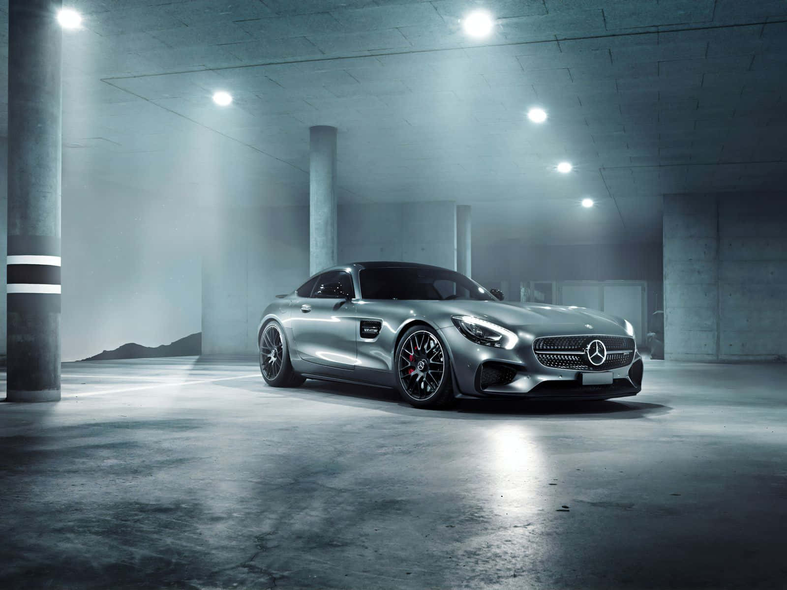 Mercedes 桌布 壁紙 — 一輛時尚的銀色 Mercedes-AMG GT 跑車在霧氣瀰漫的混凝土地下車庫中，在明亮的聚光燈下閃閃發光。