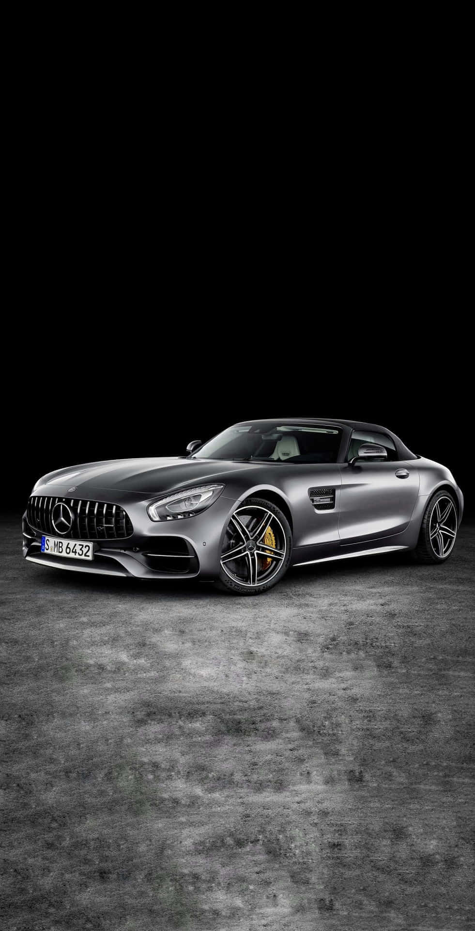 Mercedes 桌布 壁紙 — 一輛時尚的銀色 Mercedes-AMG GT Roadster 停放在紋理混凝土地板上，背景為純黑色。