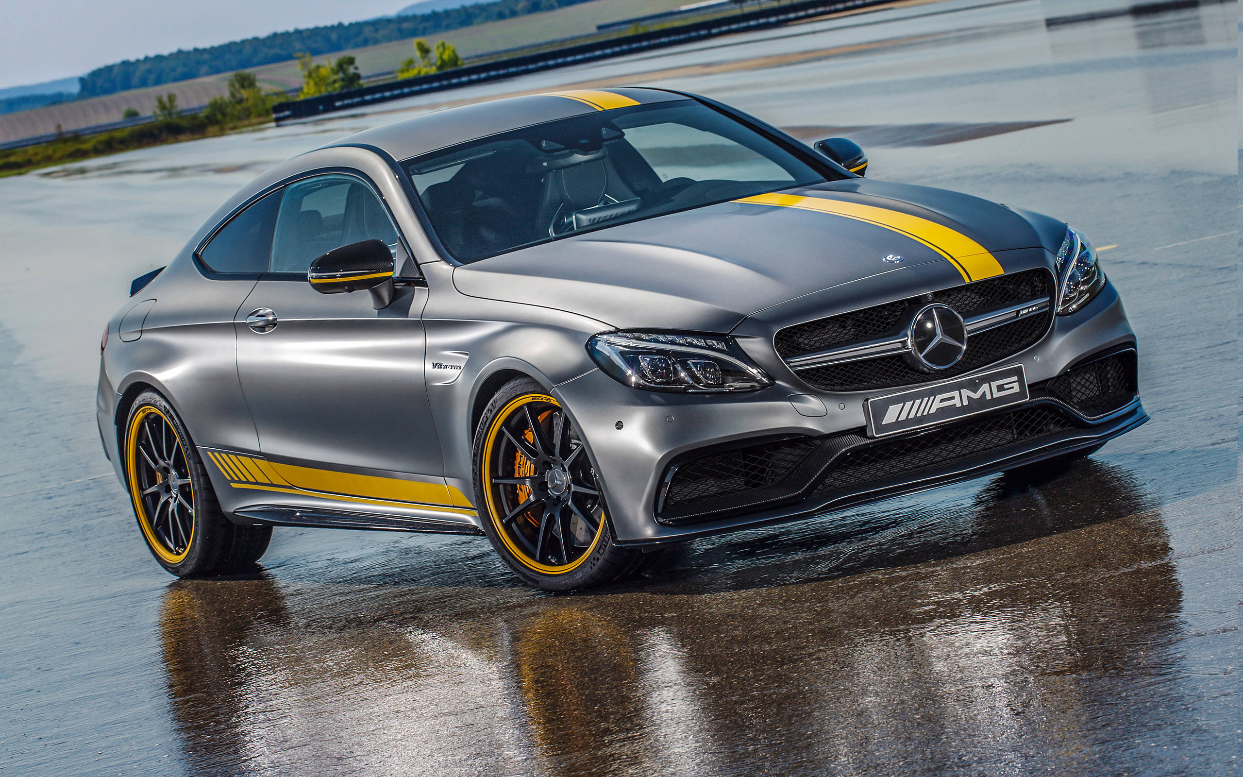 Mercedes Benz Amg 桌布 壁紙 — 一輛時尚的銀色 Mercedes-AMG C63 Coupe 帶有醒目的黃色條紋，在明亮的日光下在潮濕的賽道上閃閃發光。