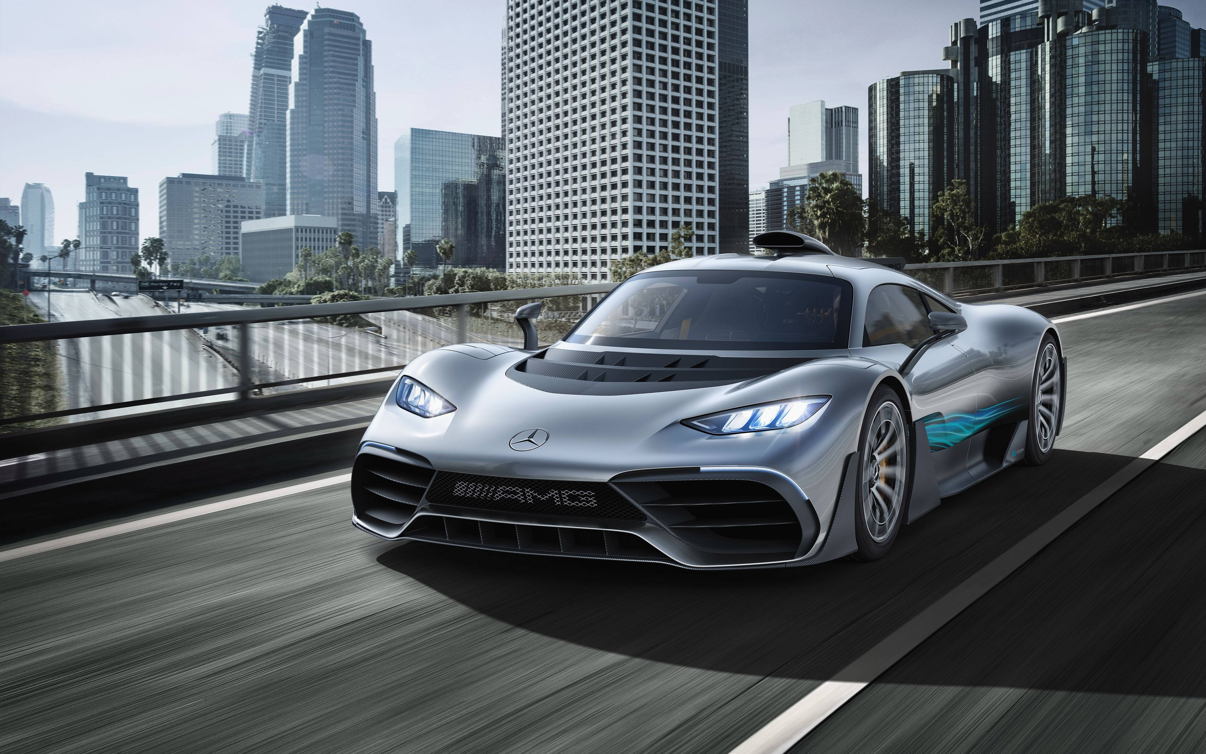 cars 桌布 壁紙 — 一輛時尚的銀色 Mercedes-AMG 跑車在城市橋樑上奔馳，背景是高樓大廈。
